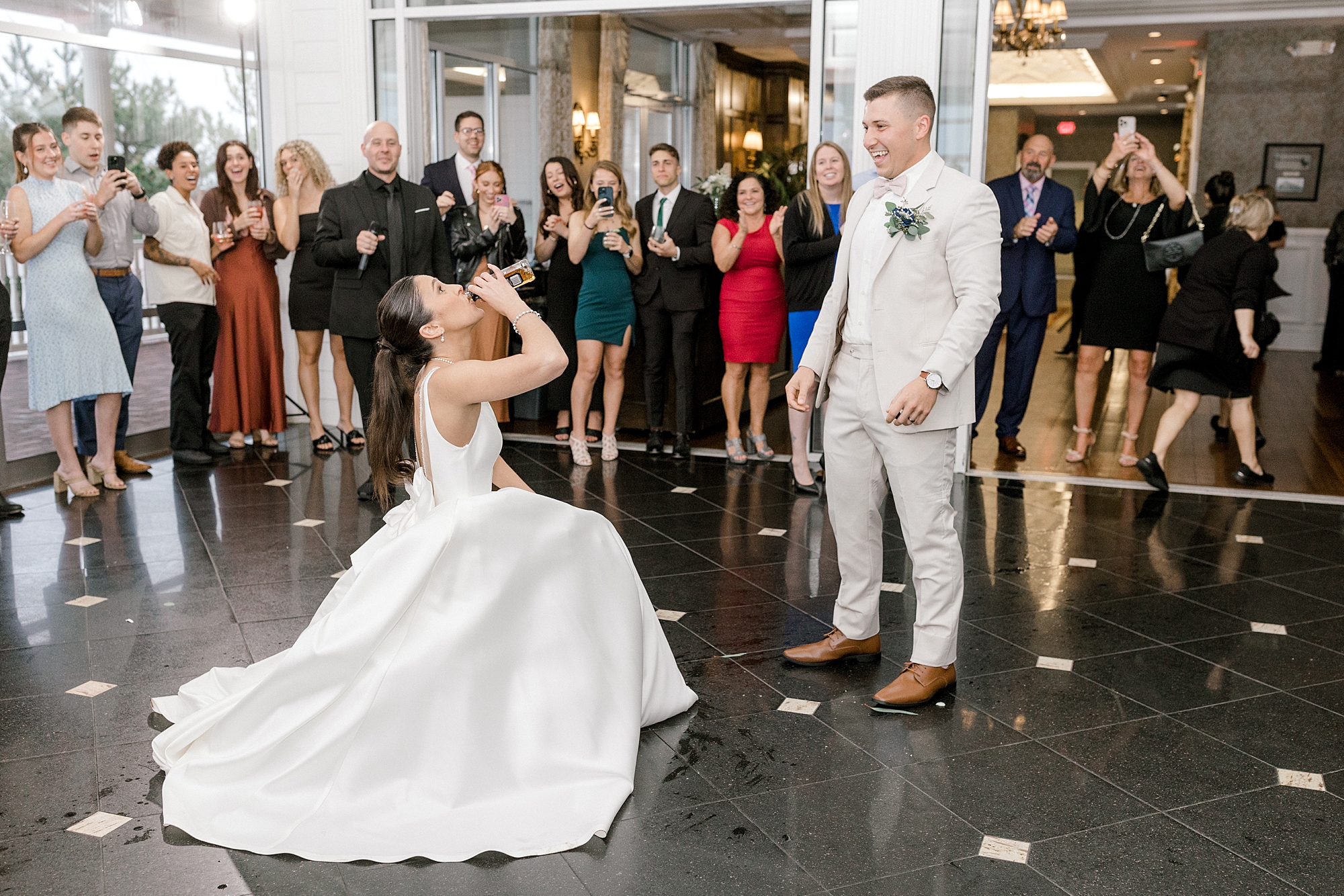 bride kneels down drinking Smirnoff ice while groom watches