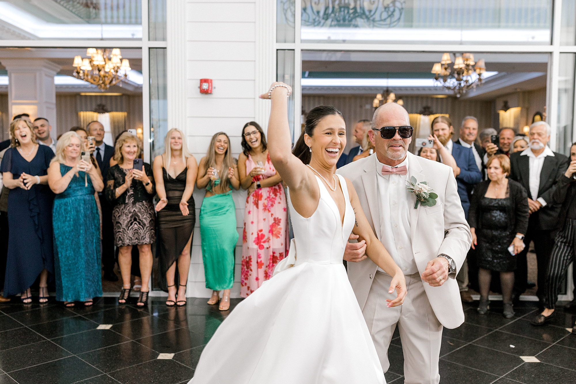 bride waves to guests with dad in sunglasses