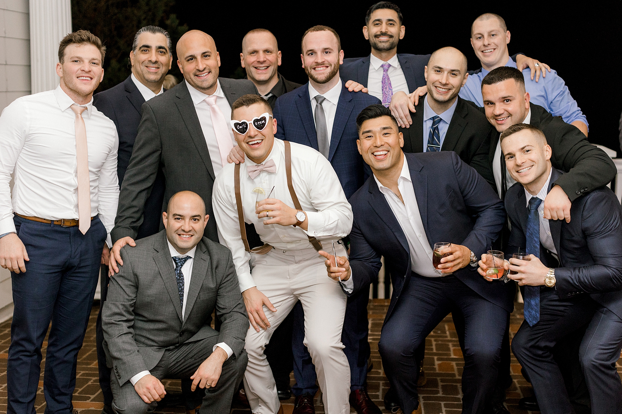 groom poses with groomsmen at reception wearing sunglasses