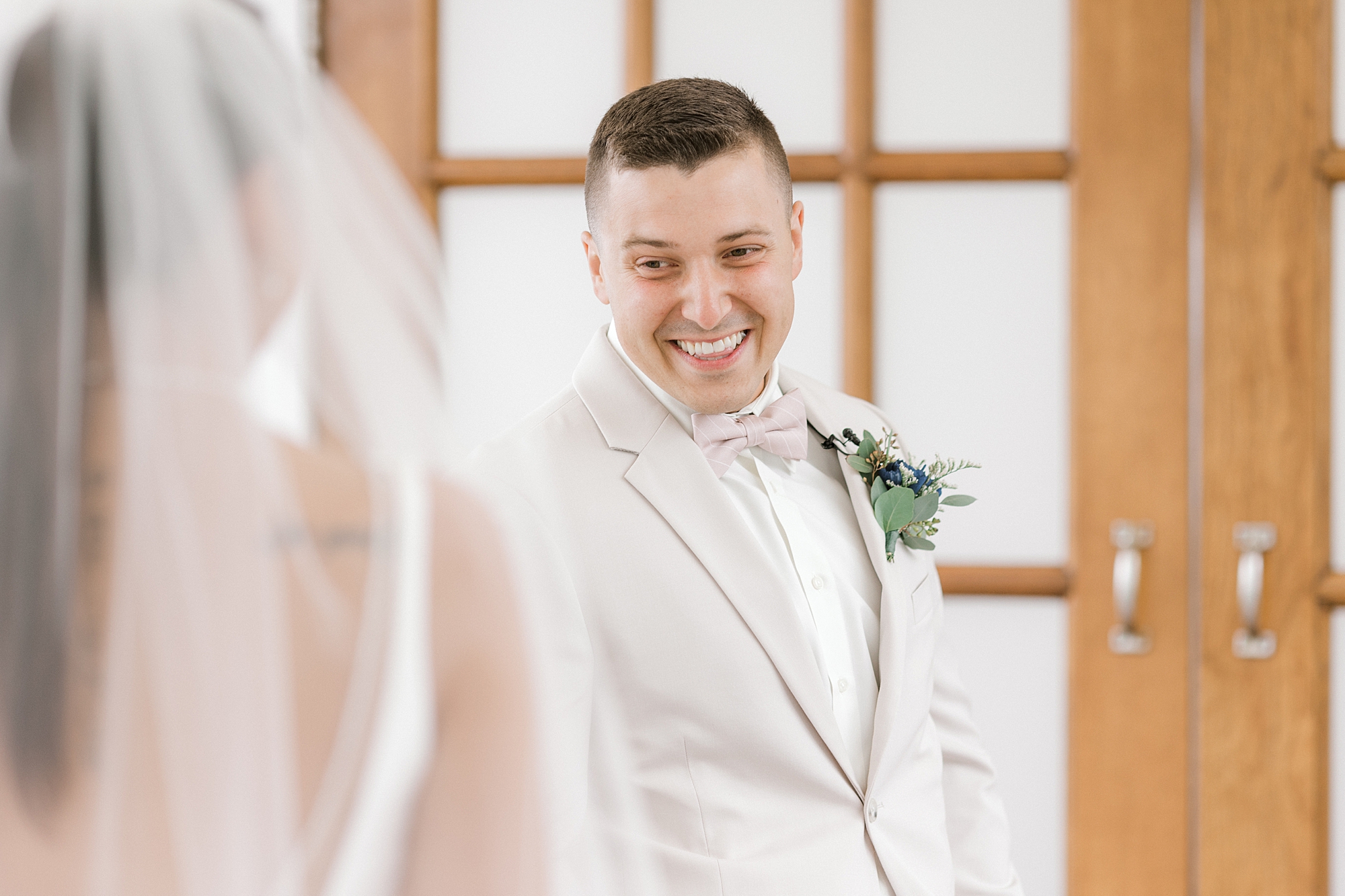 groom grins as he turns to look at bride during first look