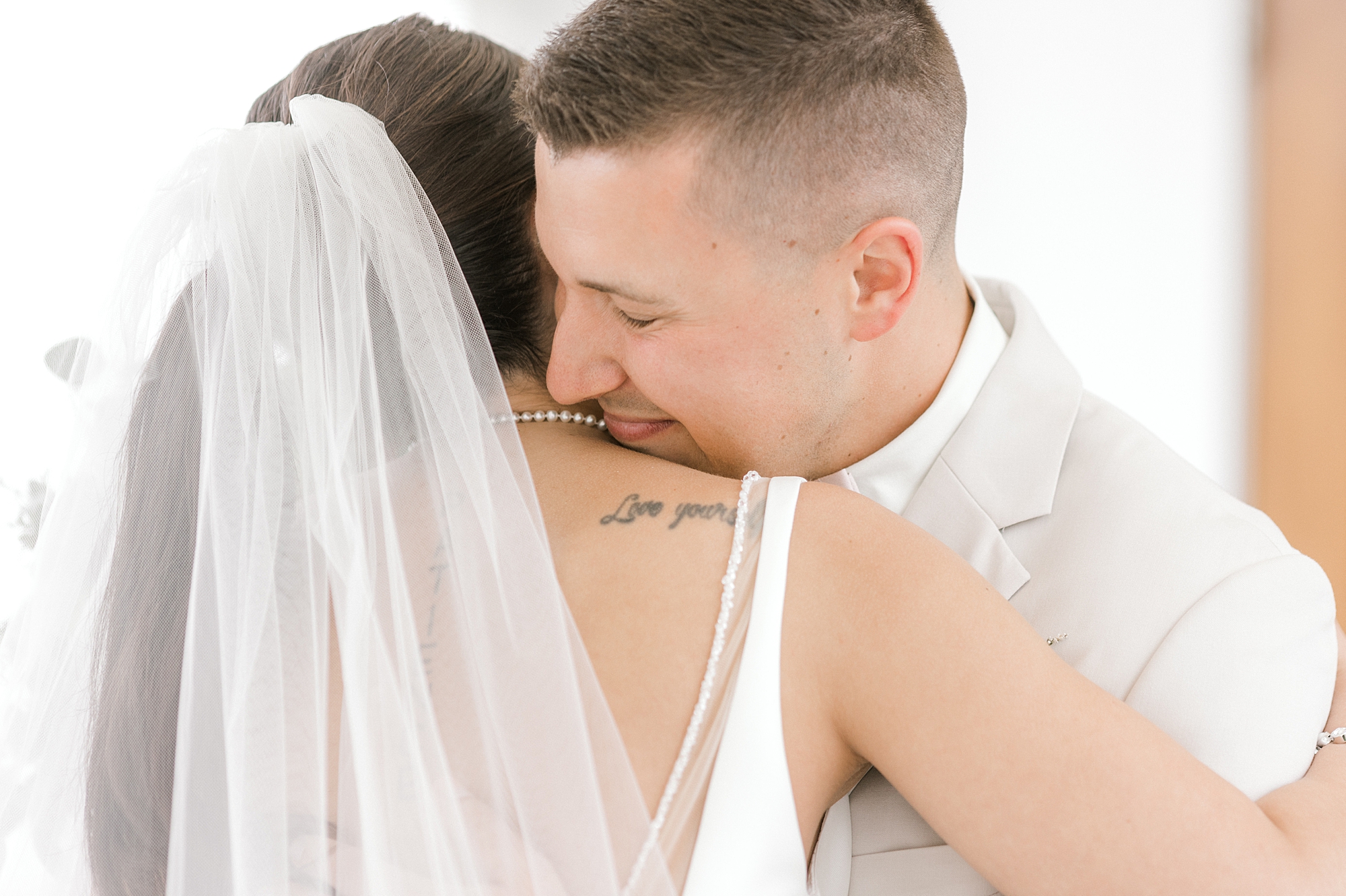groom nuzzles bride's neck holding her during first look