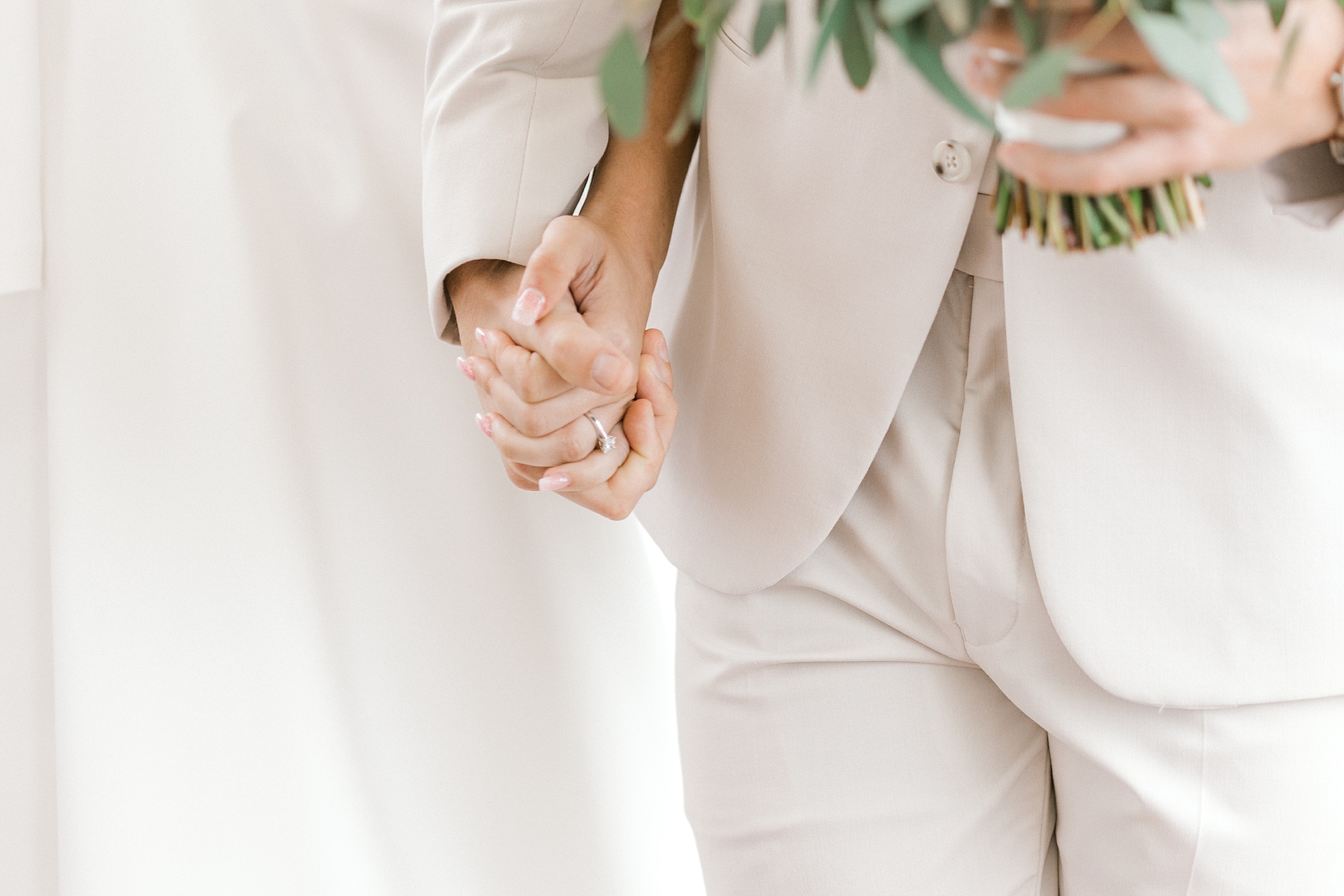 bride and groom hold hands while groom holds bride's bouquet
