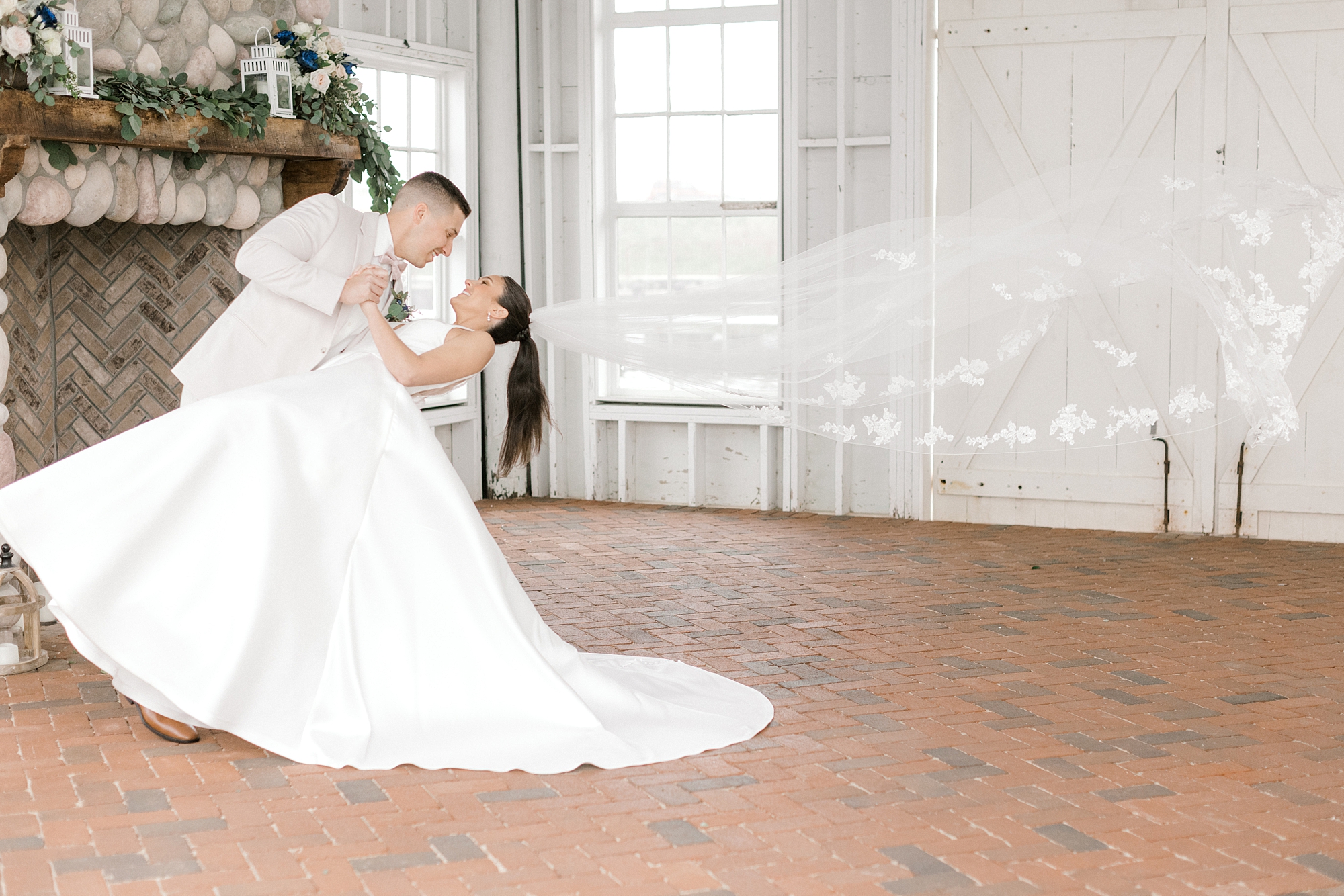 groom dips bride with veil floating behind them in ballroom at Mallard Island Yacht Club