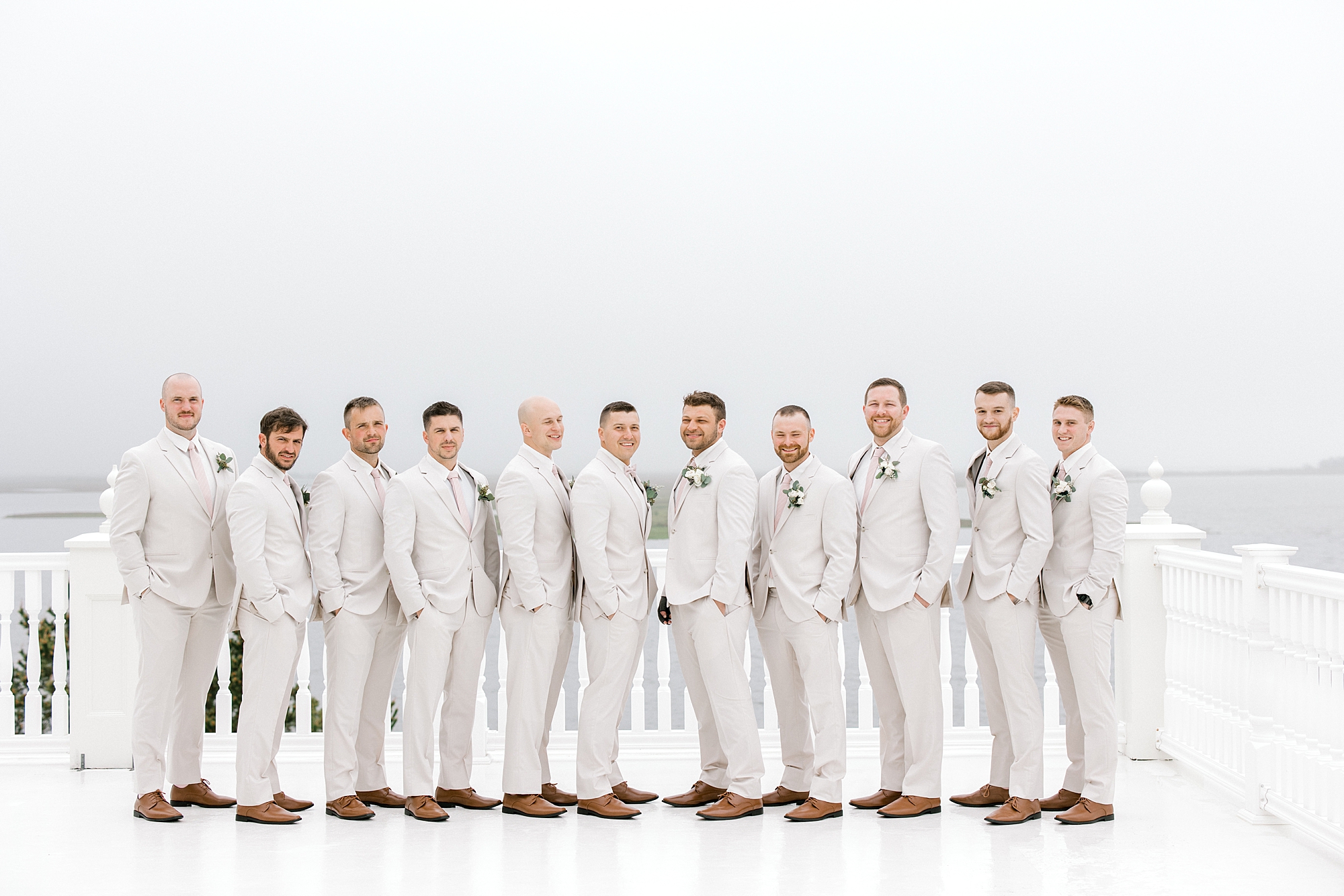 groom stands with groomsmen in ivory suits at Mallard Island Yacht Club