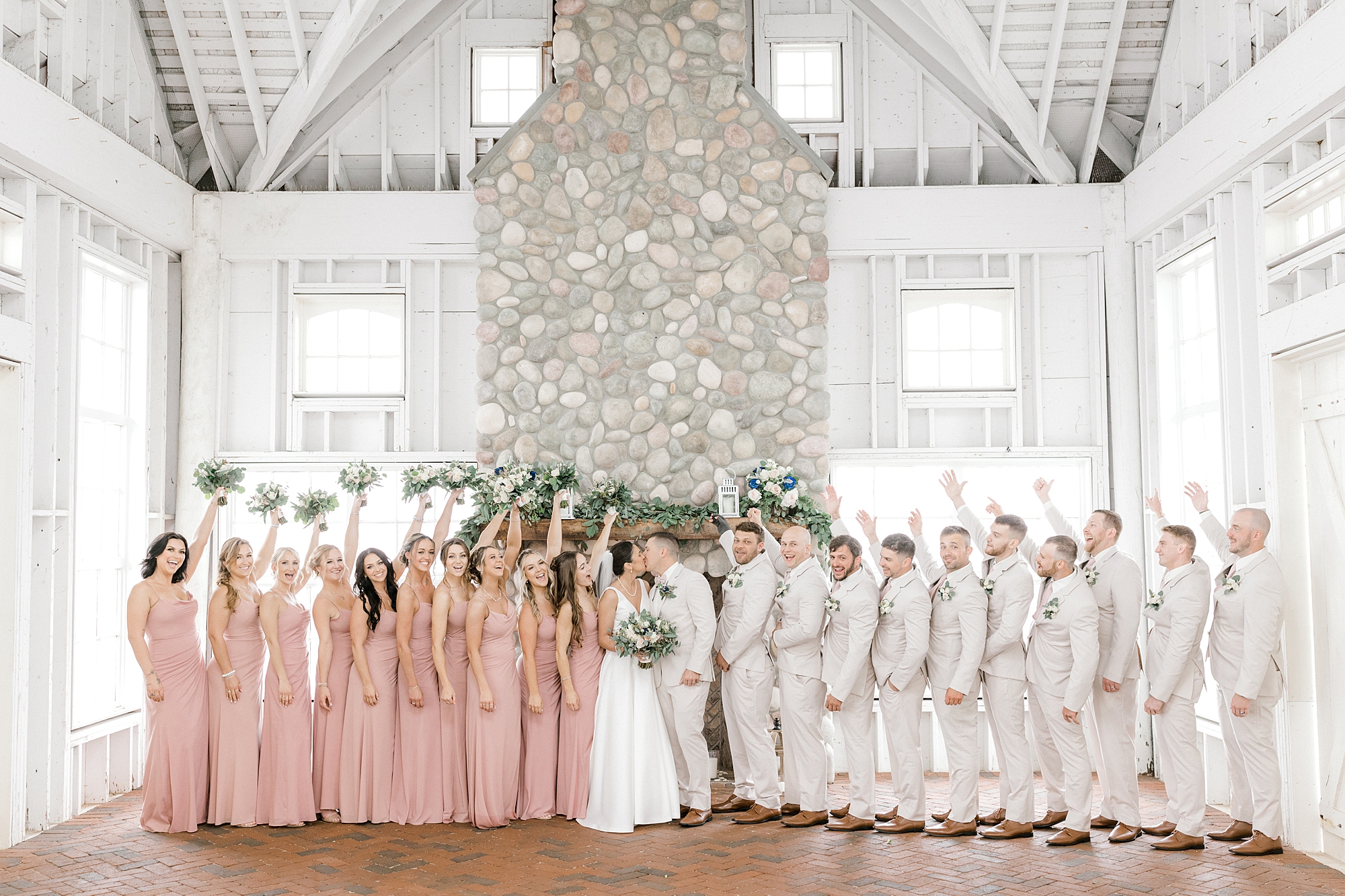 bride and groom pose with wedding party in dusty pink gowns and tusk suits