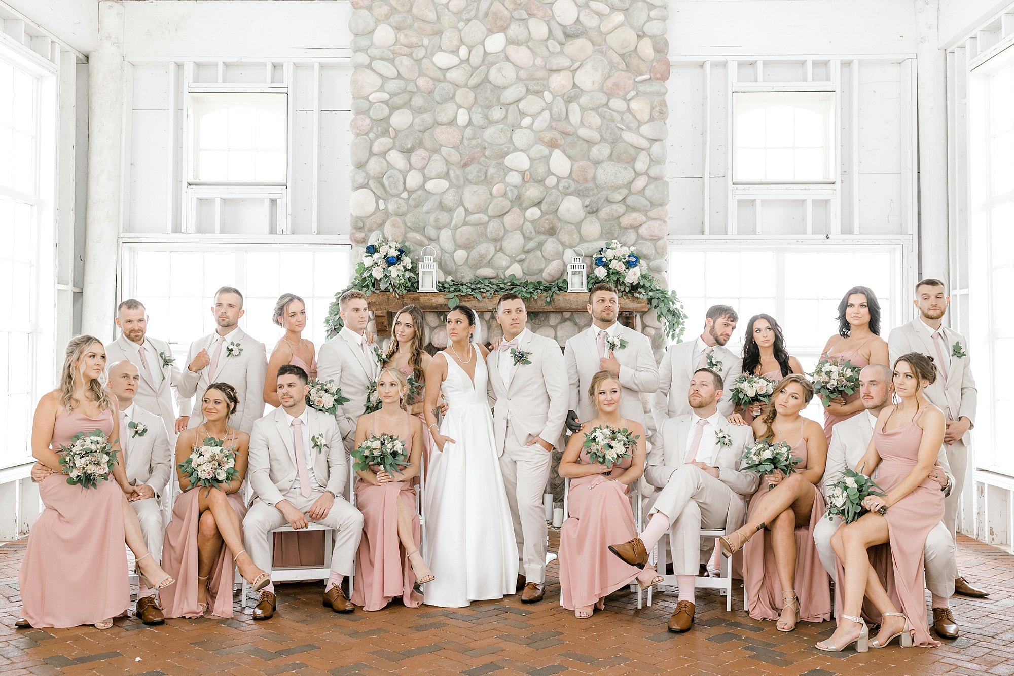 bride and groom stand with wedding party in ivory suits and dusty pink gowns