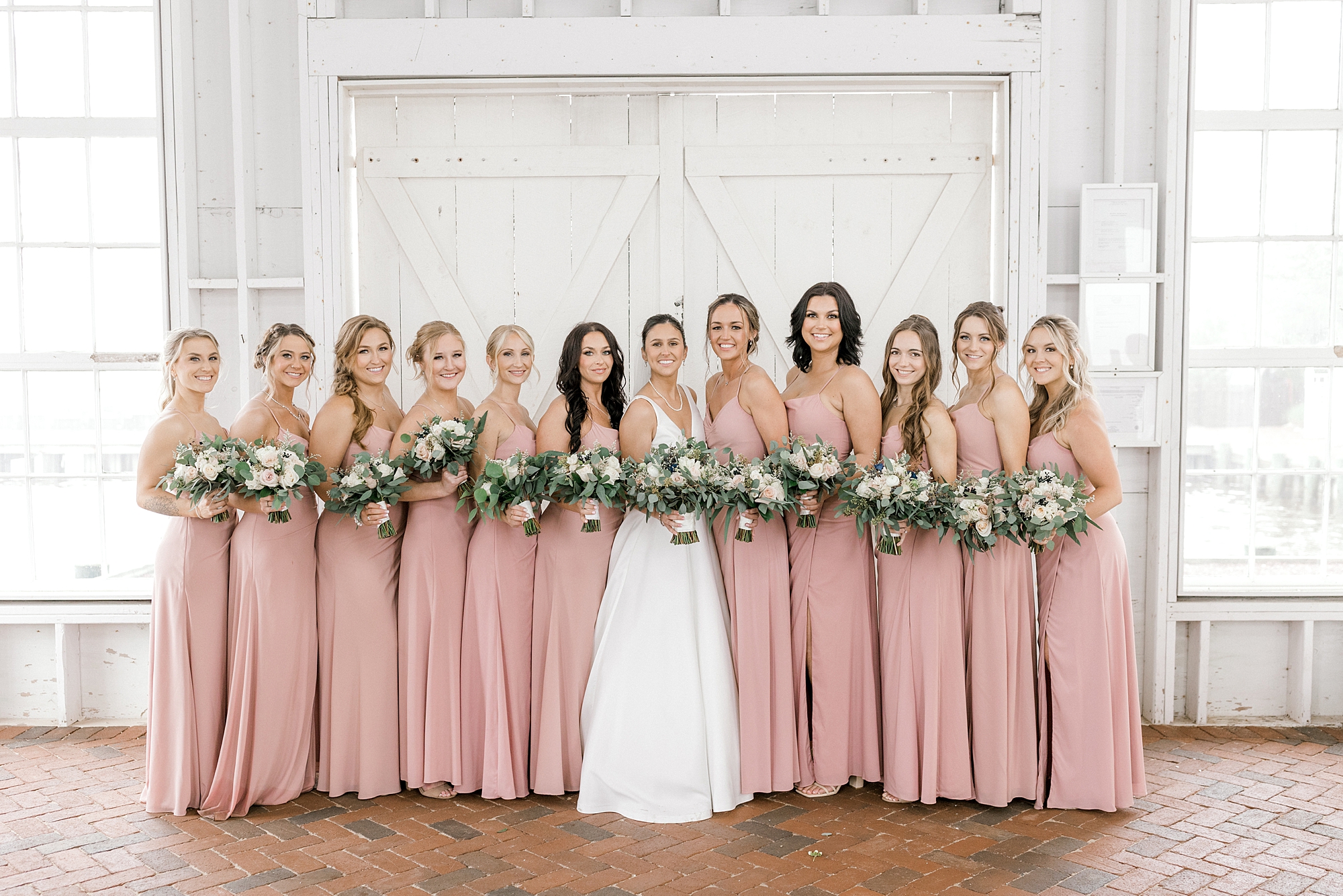 bride stands with bridesmaids in dusty pink dresses