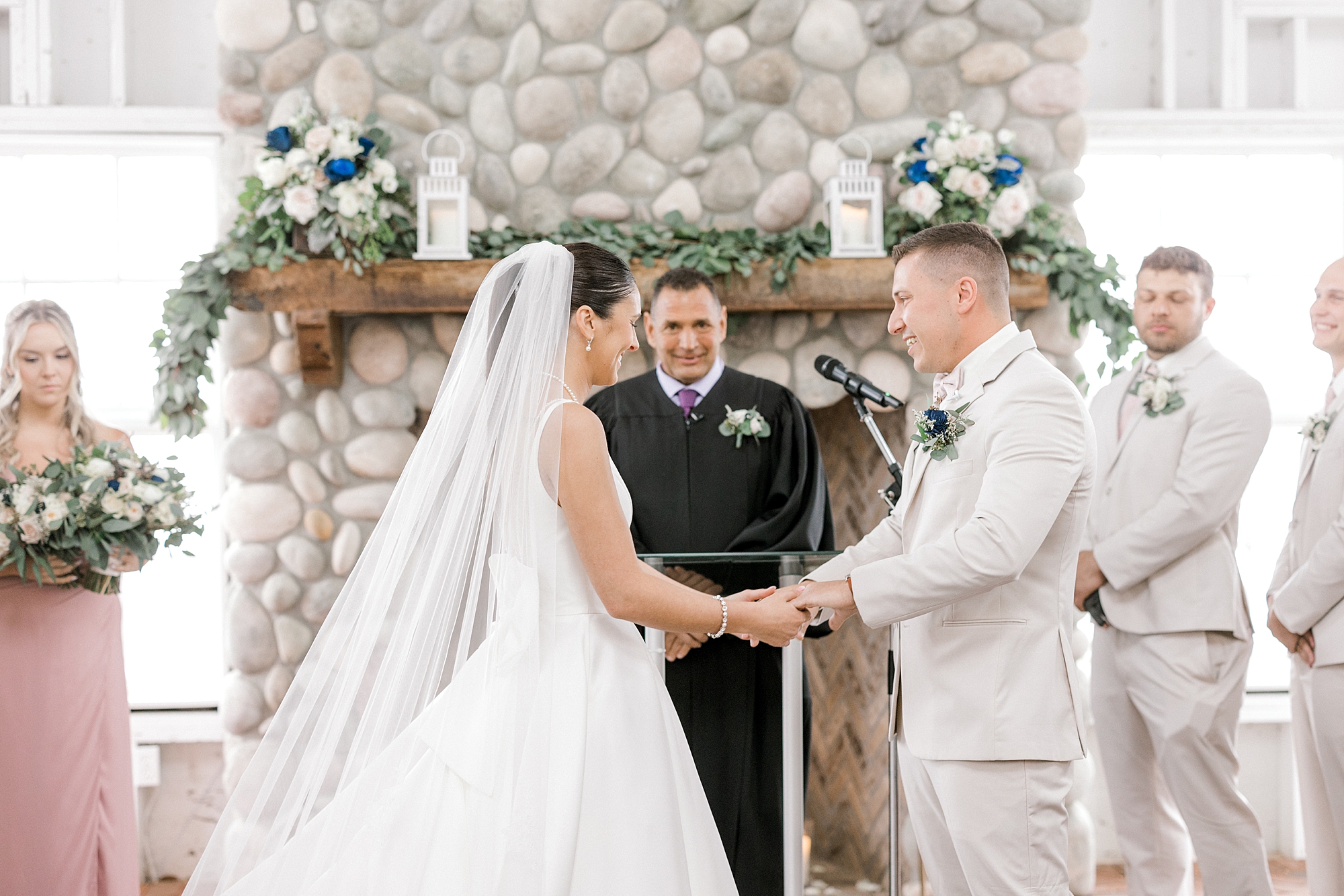 bride and groom hold hands by stone fireplace at Mallard Island Yacht Club