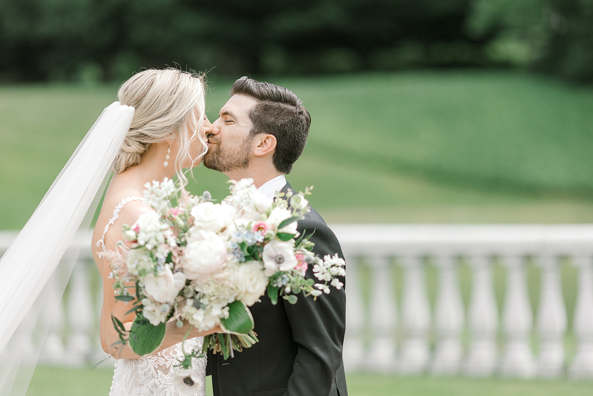 bride and groom kiss near white railing at the Ashford Estate