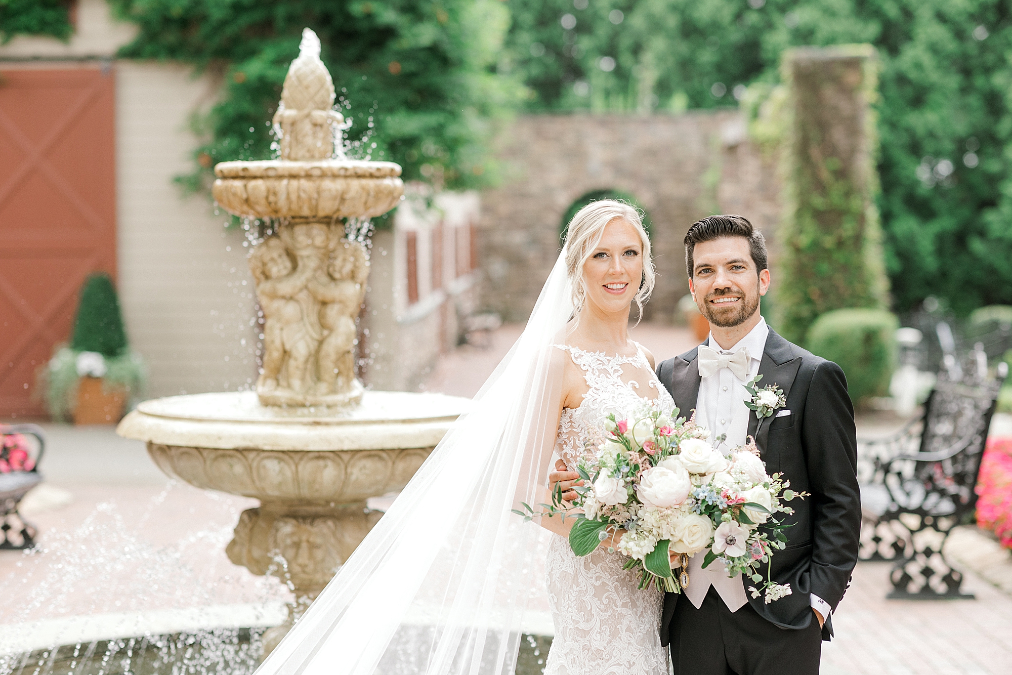 newlyweds smile near fountain in courtyard at the Ashford Estate