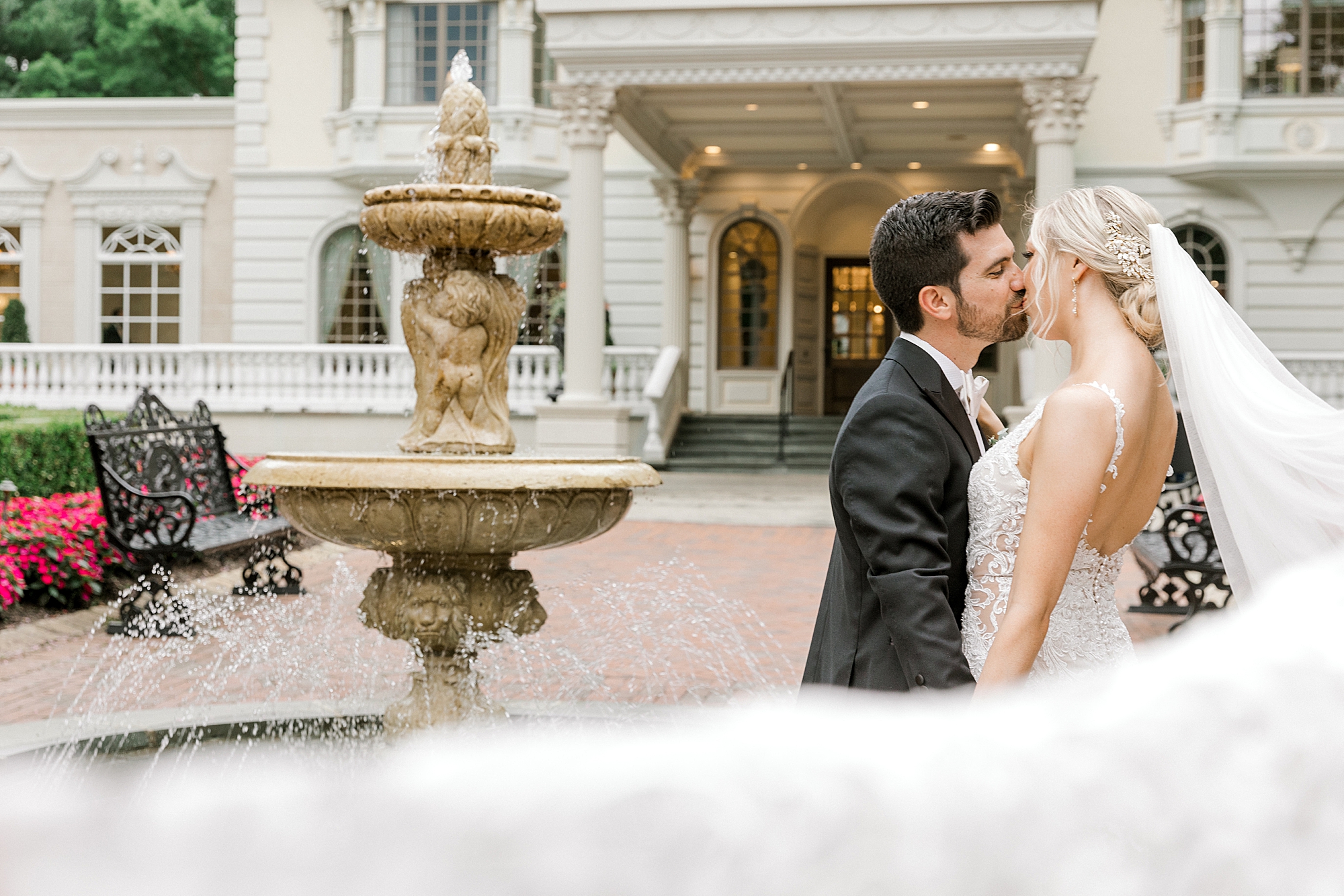 bride and groom kiss near fountain in courtyard outside the Ashford Estate