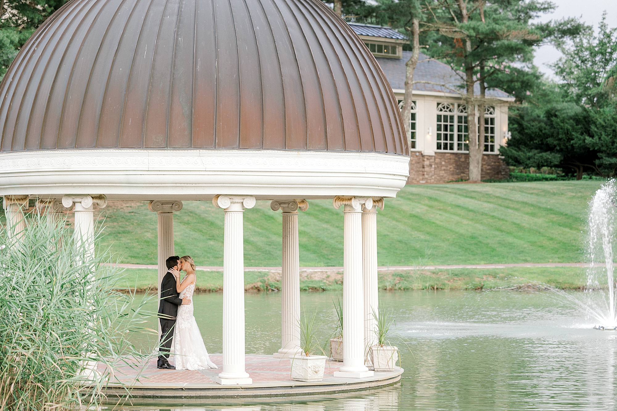 bride and groom kiss in gazebo on lake at the Ashford Estate;;