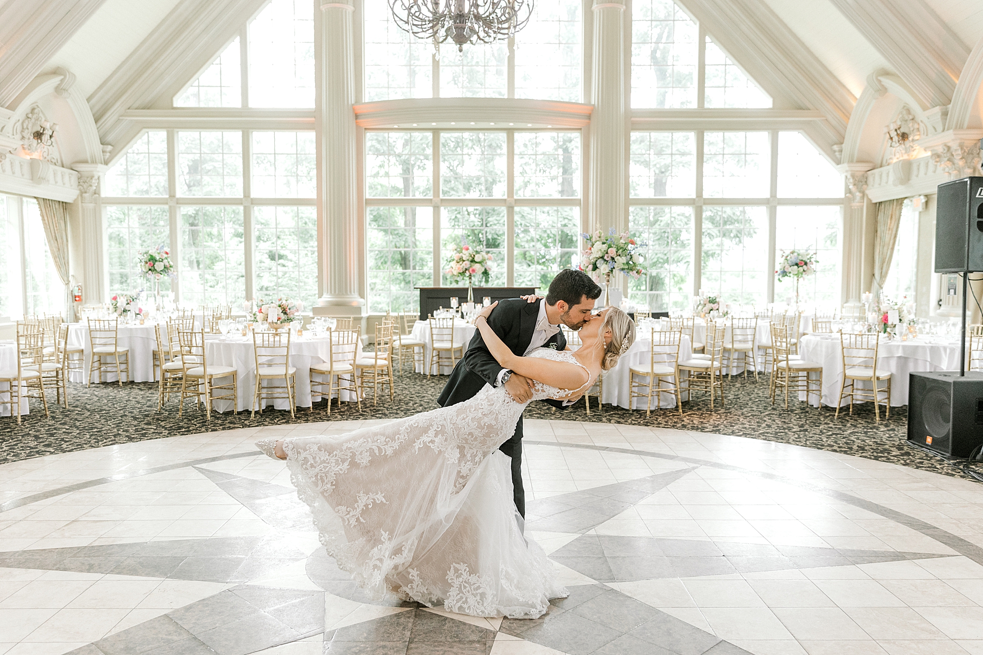 groom dips bride kissing her in empty ballroom before classic Sumer wedding reception at the Ashford Estate