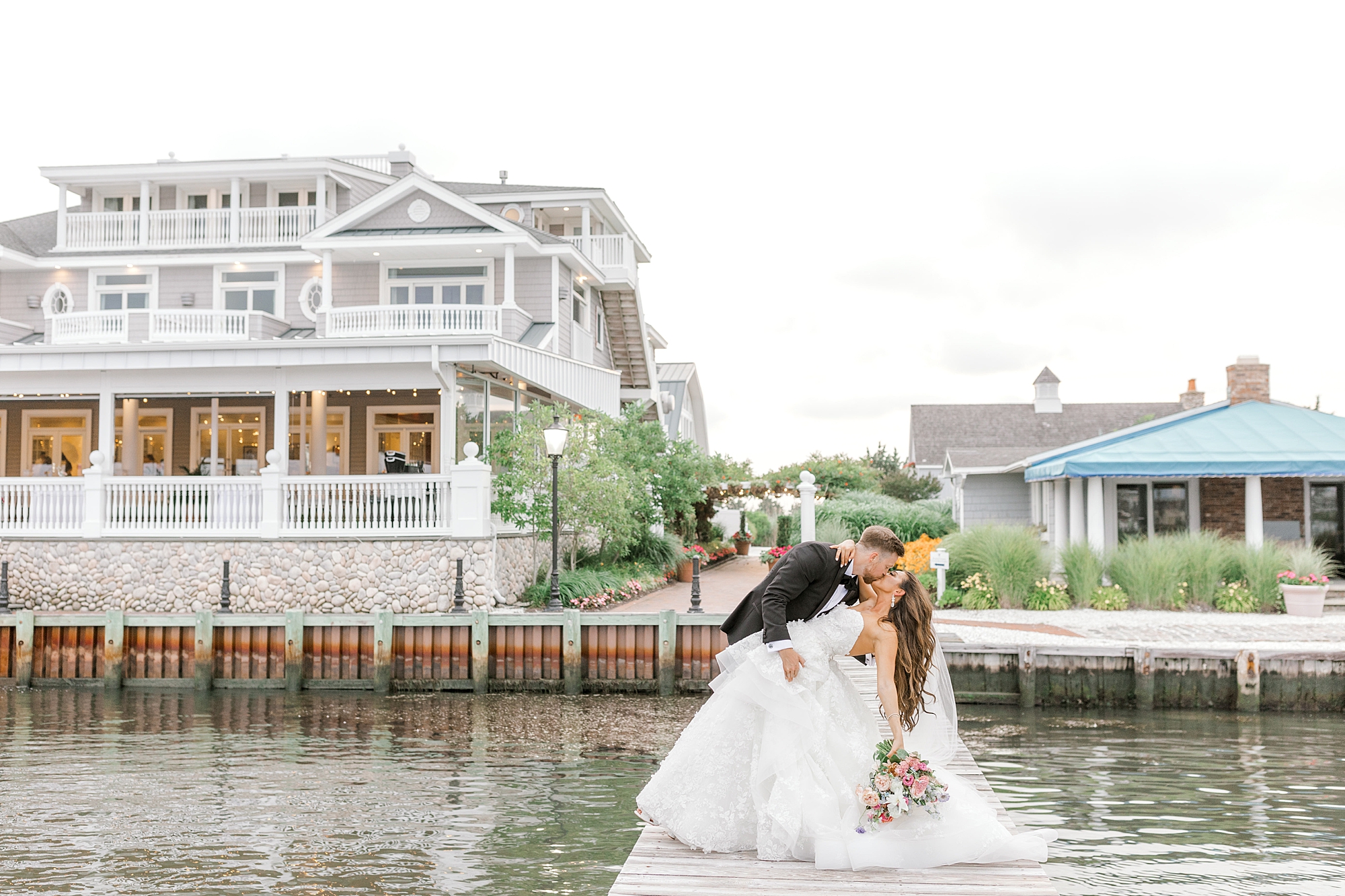 groom kisses bride dipping her on dock outside Bonnet Island Estate