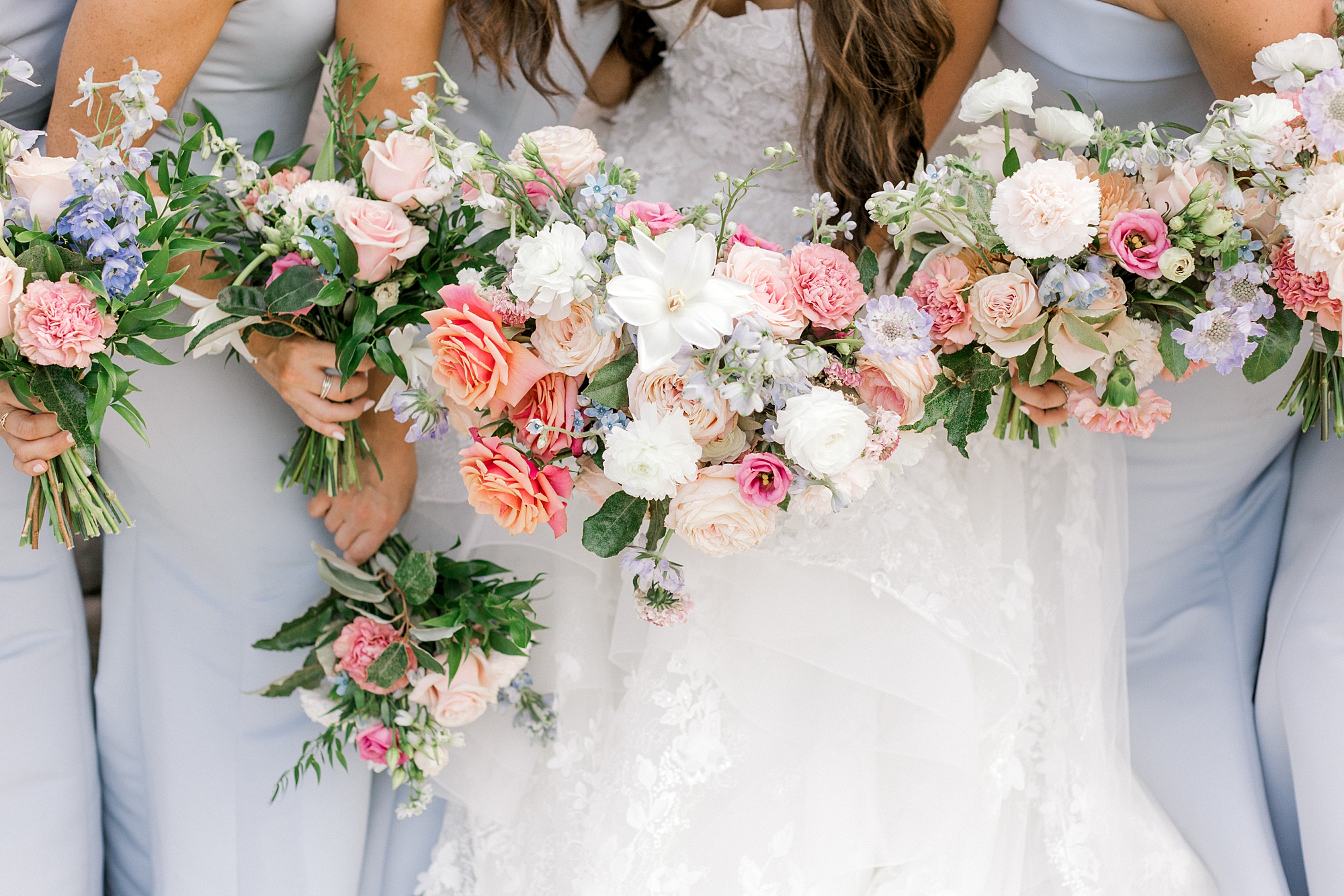 bride and bridesmaids in blue gowns hold pink and white bouquets for spring wedding