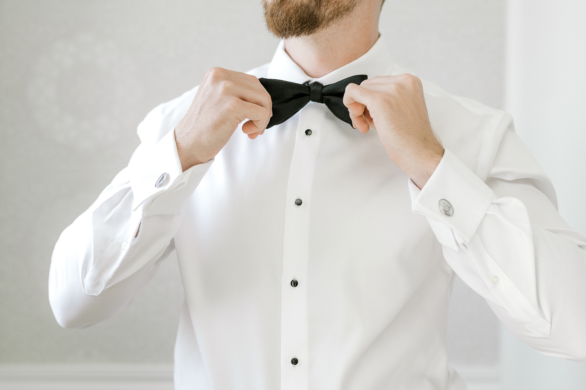 groom adjusts black bowtie of suit before LBI wedding