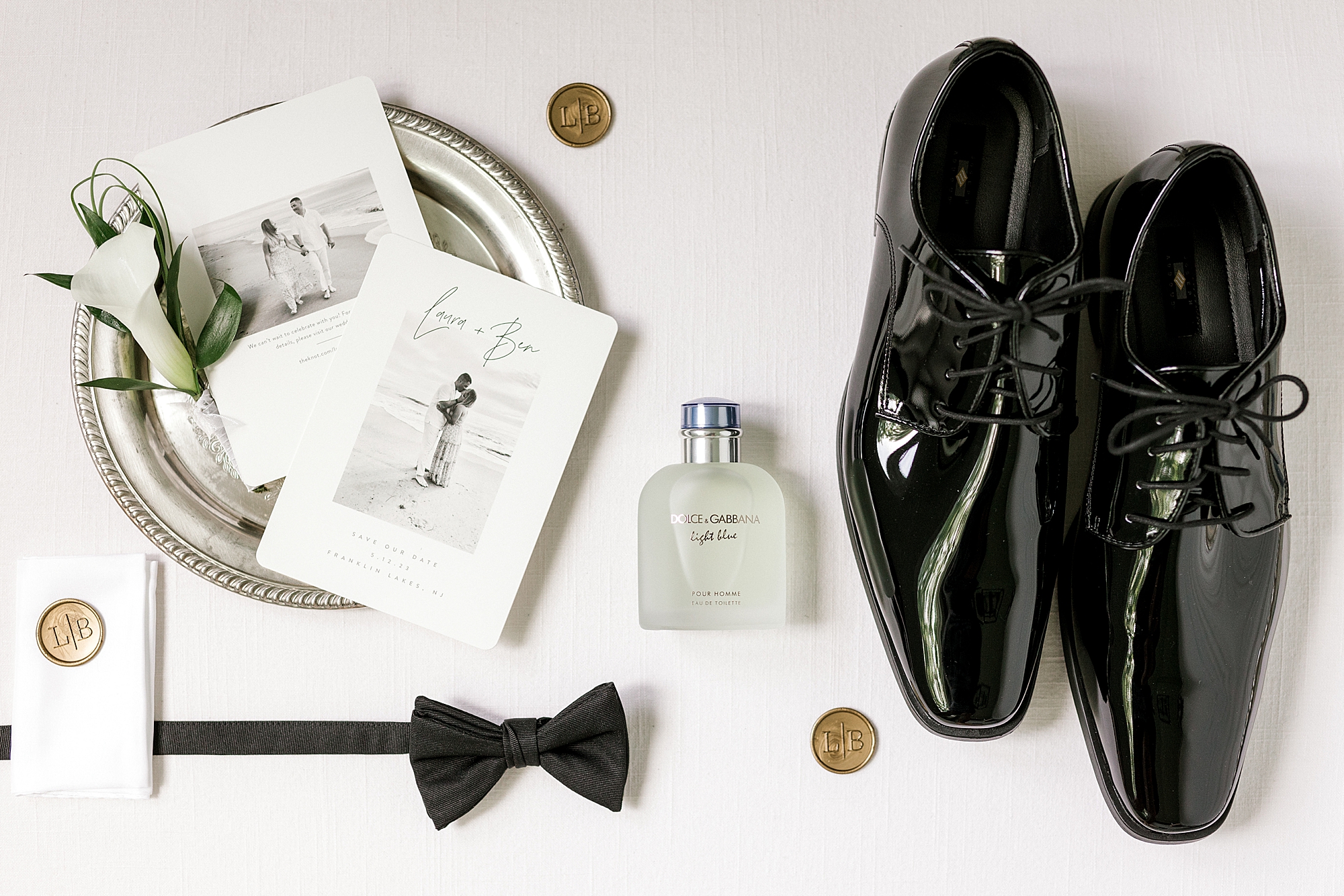 groom's black shoes and save-the-date on gold tray