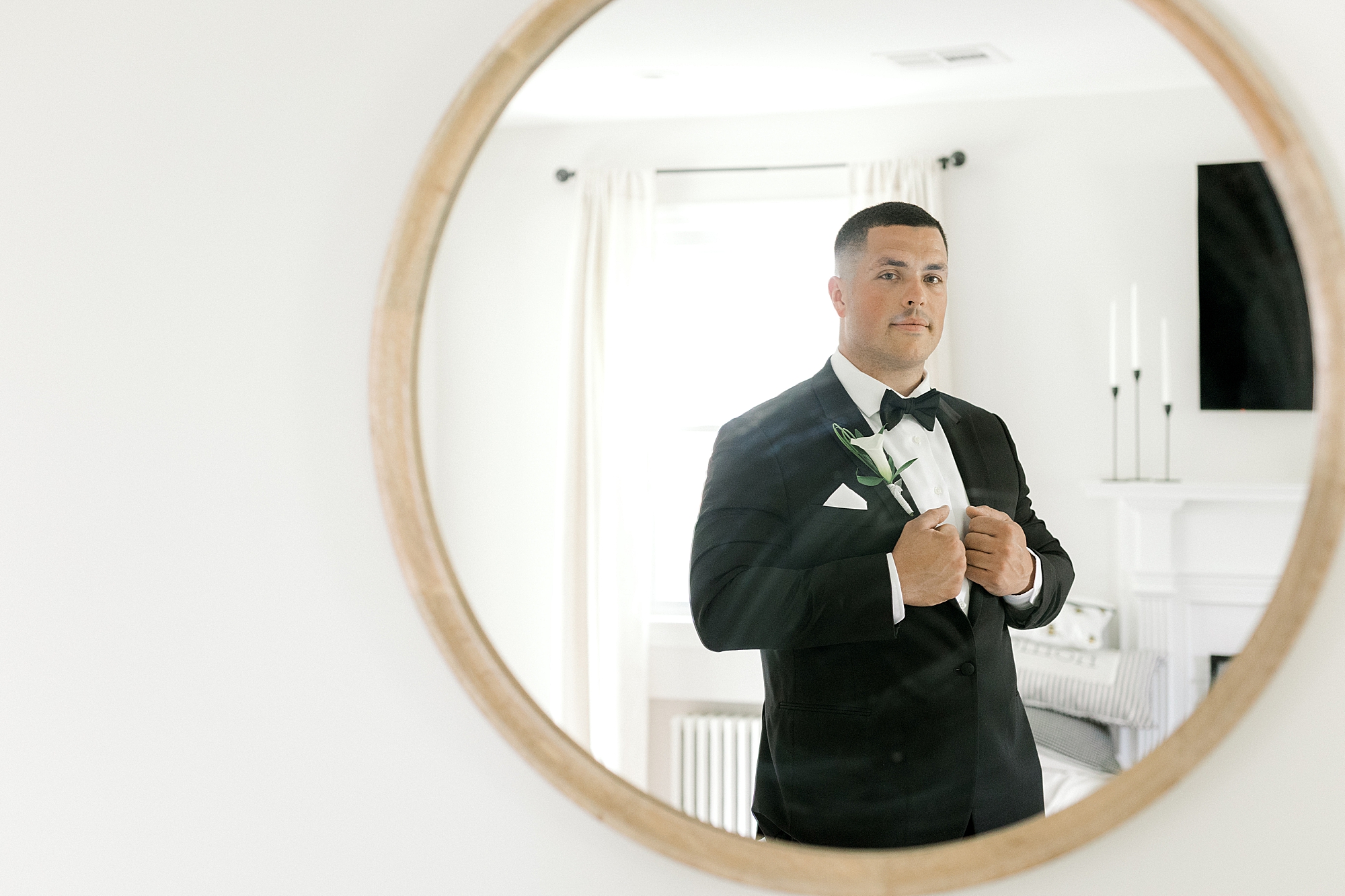groom holds lapels of black suit and looks in mirror at Indian Trail Club