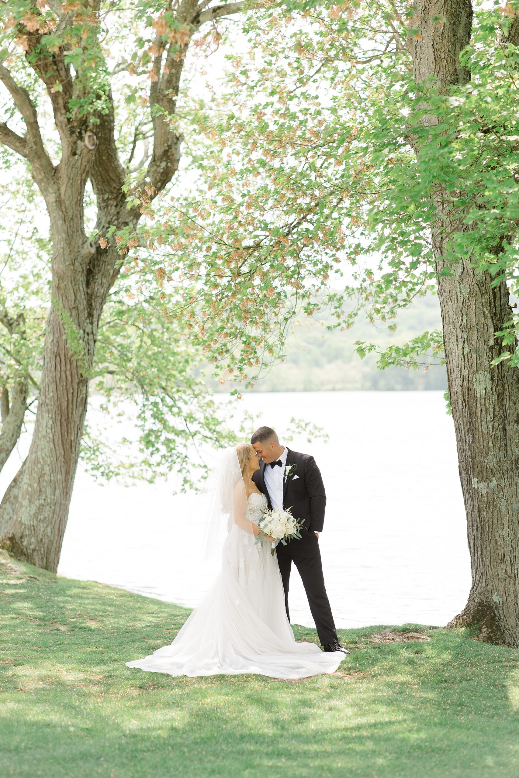 newlyweds lean heads together under trees at Indian Trail Club