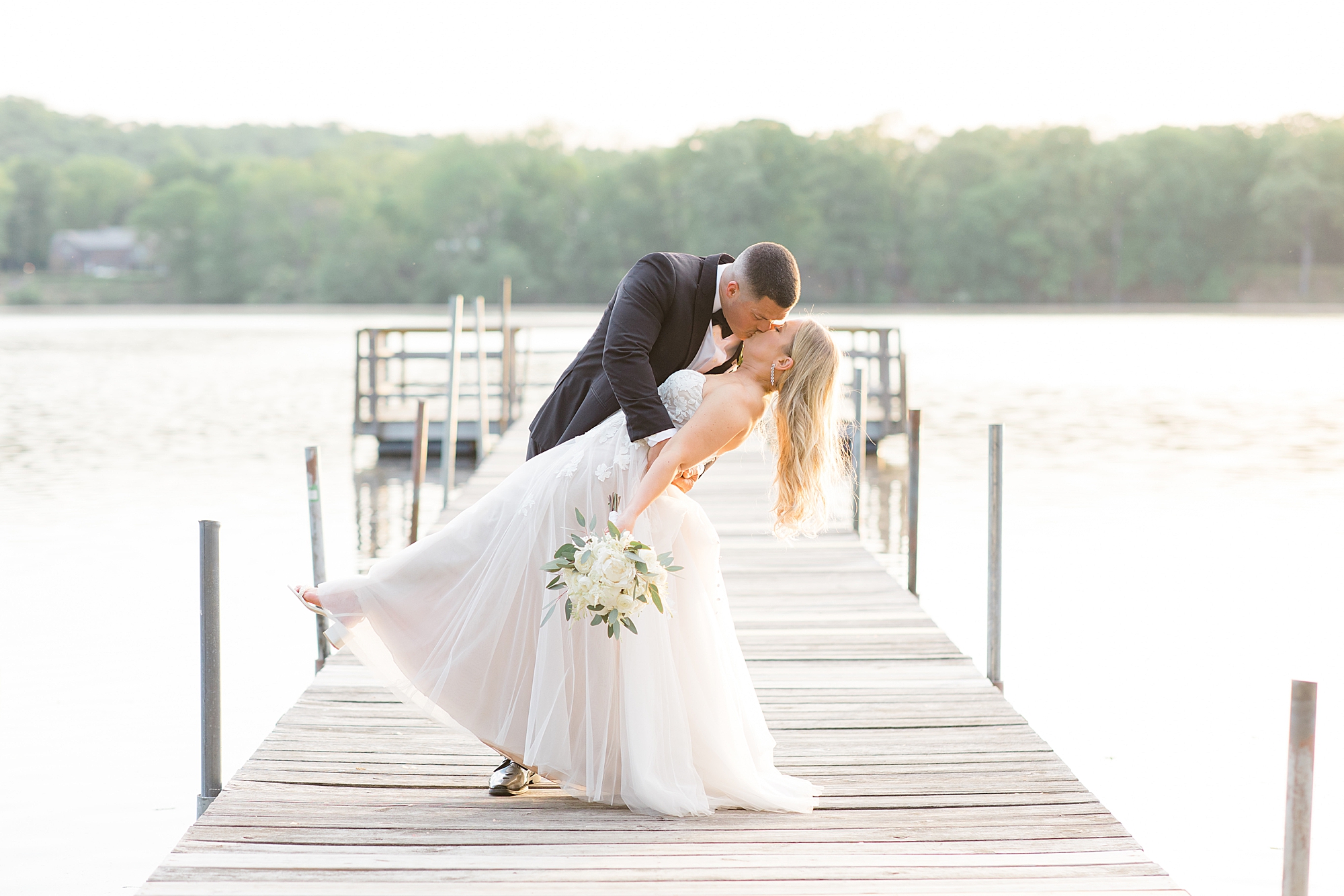 newlyweds kiss at sunset on dock at Indian Trail Club