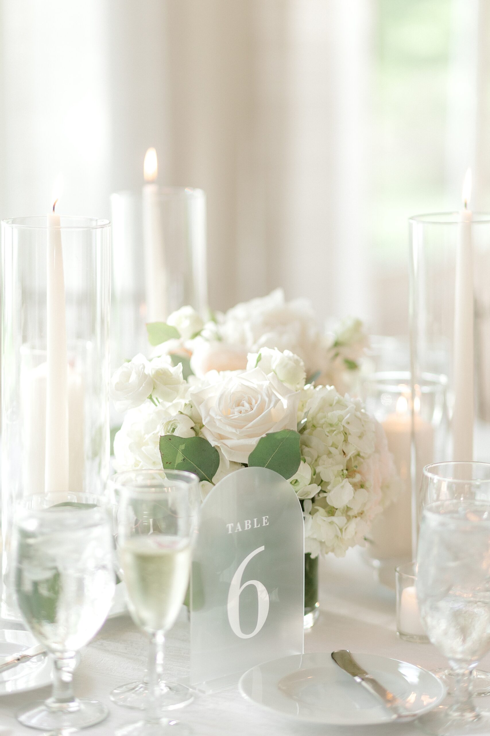 centerpieces with acrylic table numbers, tall thin white candles and white flowers
