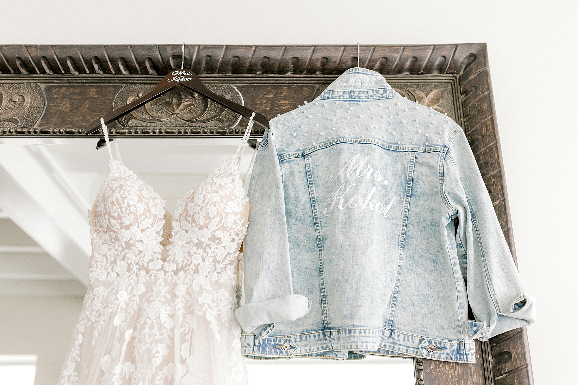 wedding dress and custom jean jacket hang on mirror frame