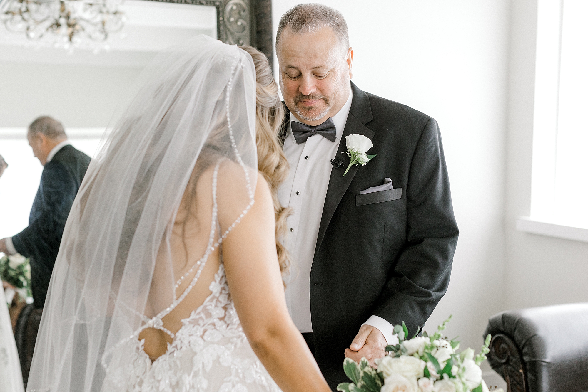 father looks down at bride during first look in suite at the Refinery at Perona Farms