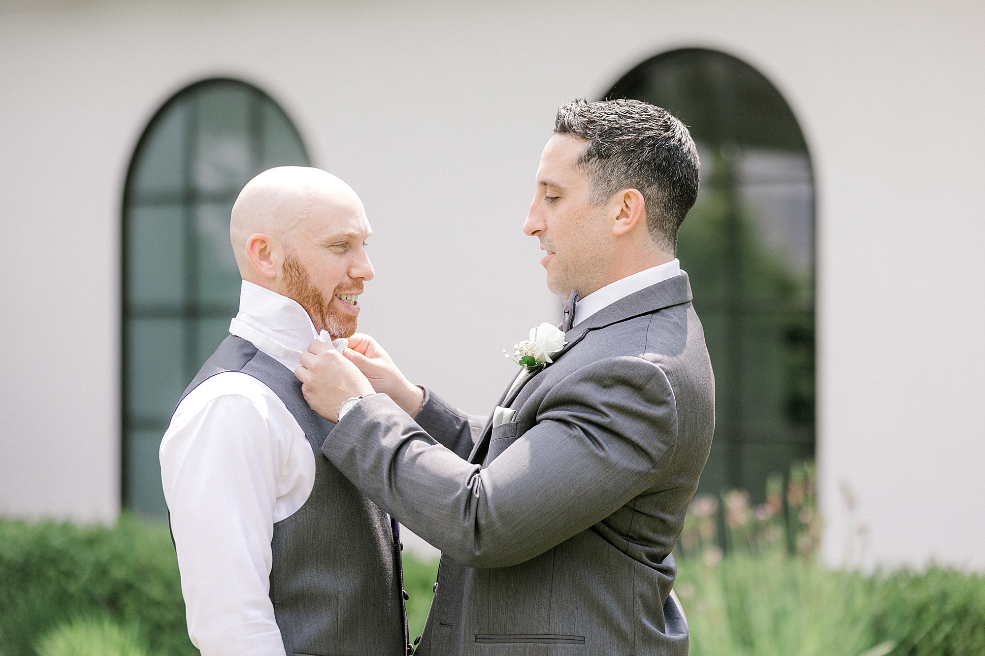 groomsman in grey suit adjust groom's collar
