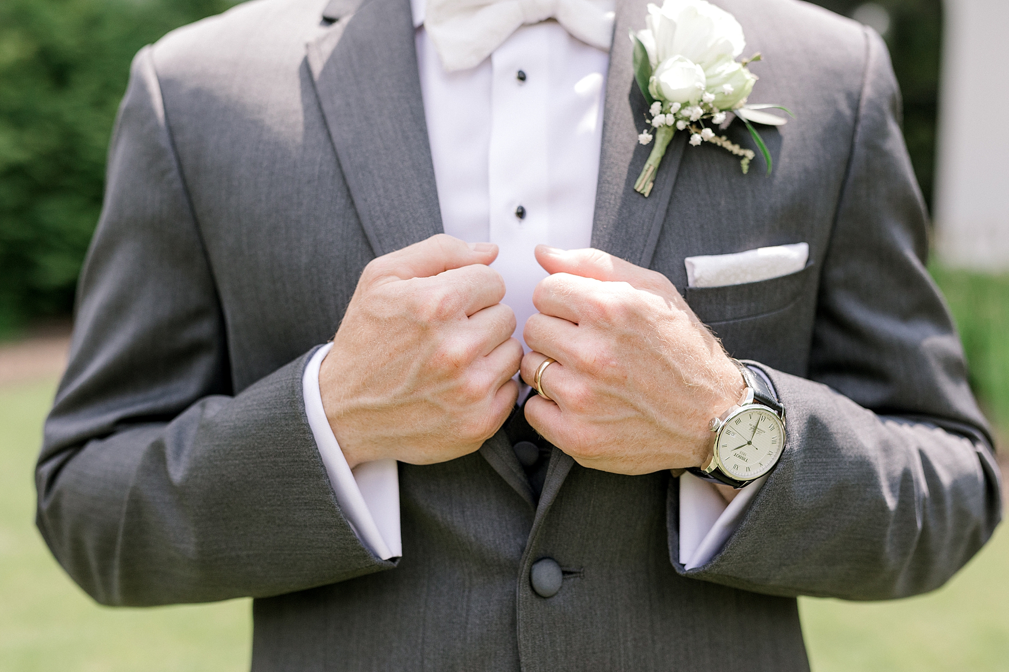 groom holds lapels of grey suit