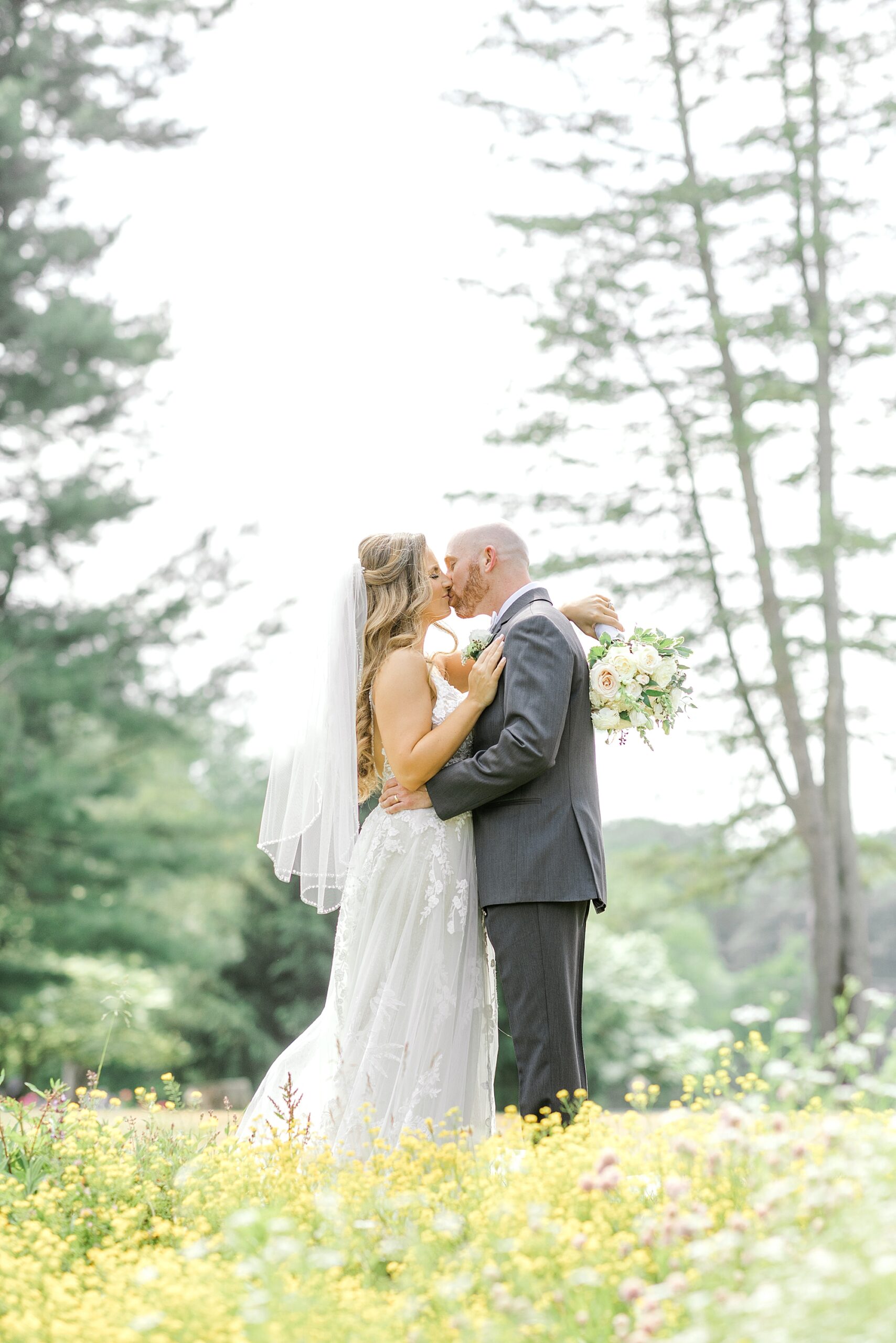 bride and groom kiss in yellow wildflower field at the Refinery at Perona Farms