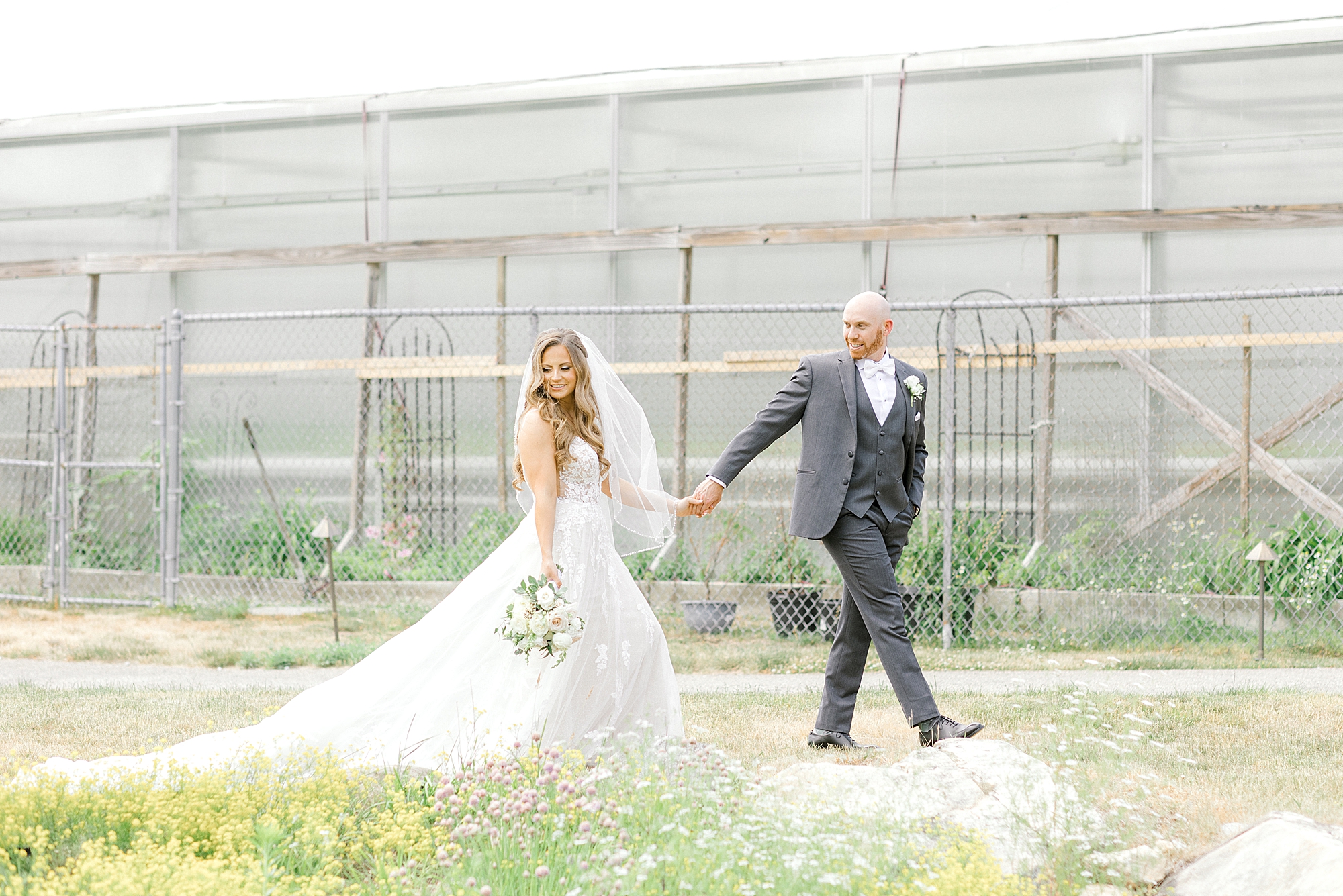 bride and groom hold hands walking by greenhouse at the Refinery at Perona Farms