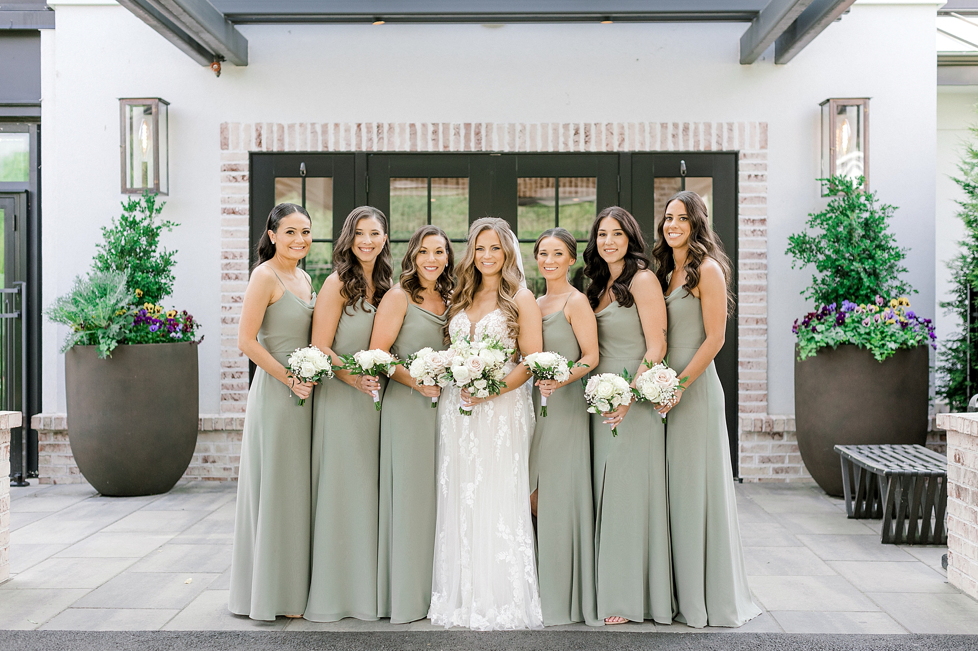 bride poses with bridesmaids in sage green gowns