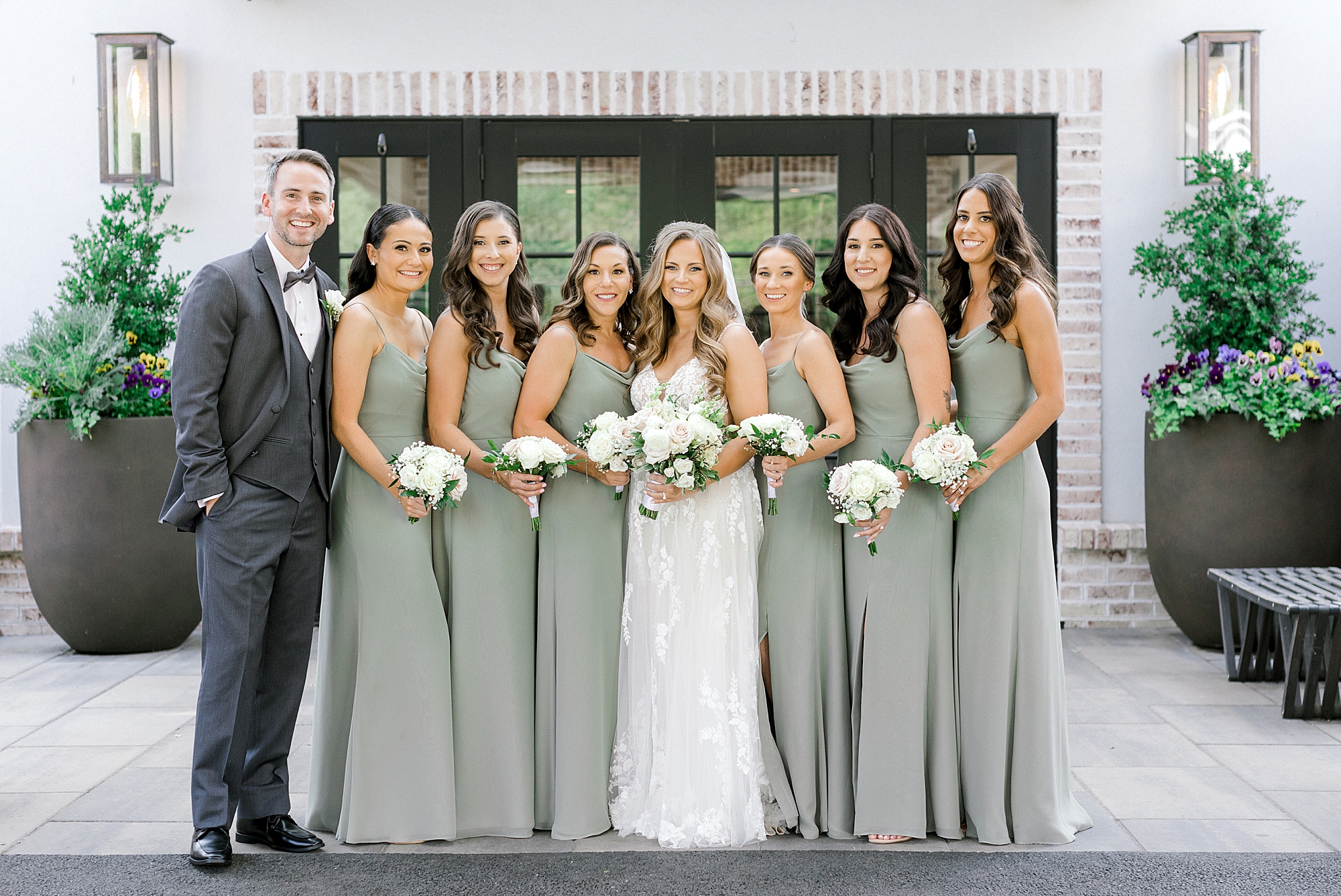 bride stands with groomsman and bridesmaids outside the Refinery at Perona Farms