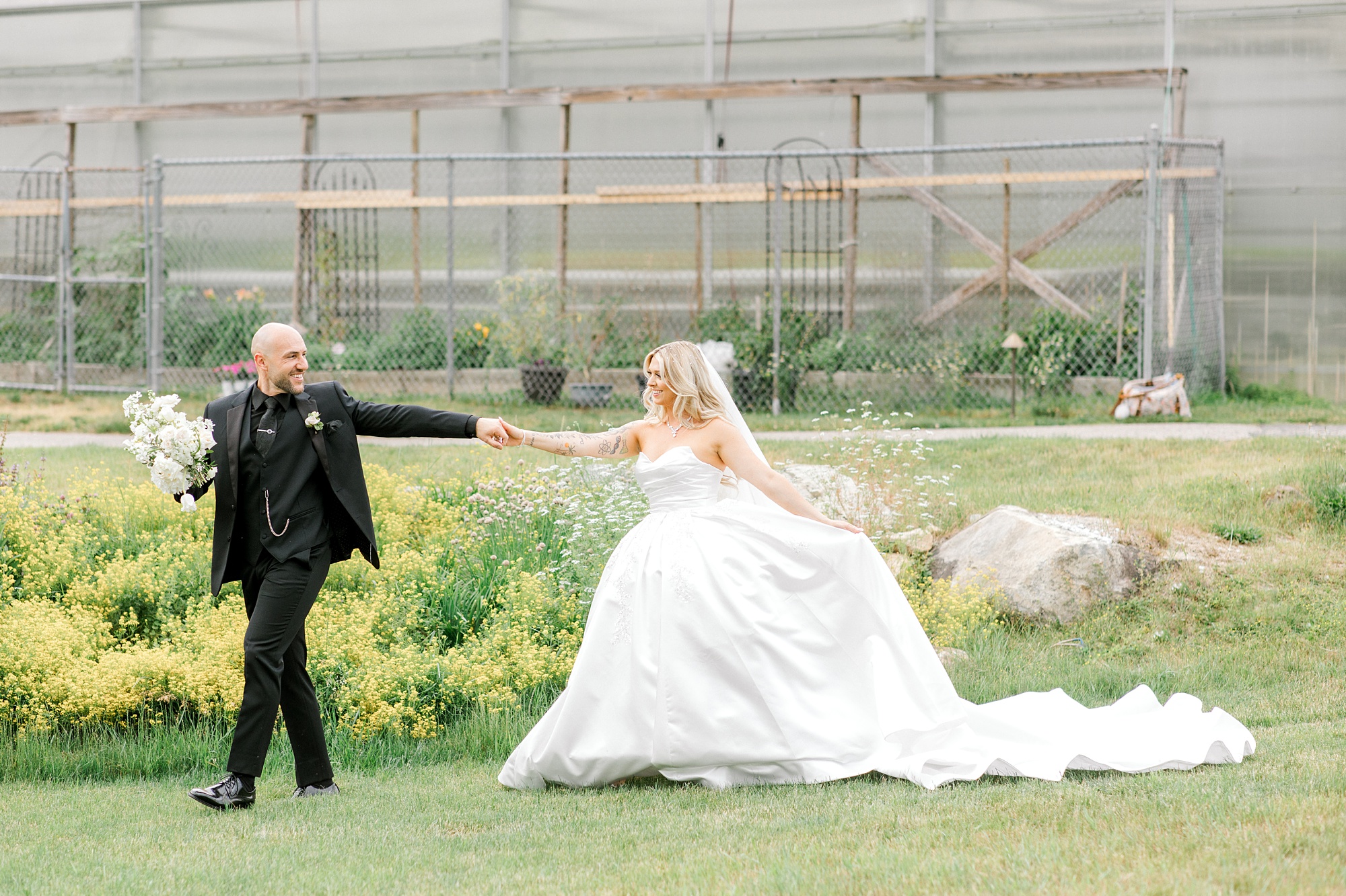 groom holds bride's hand leading her across field of wildflowers