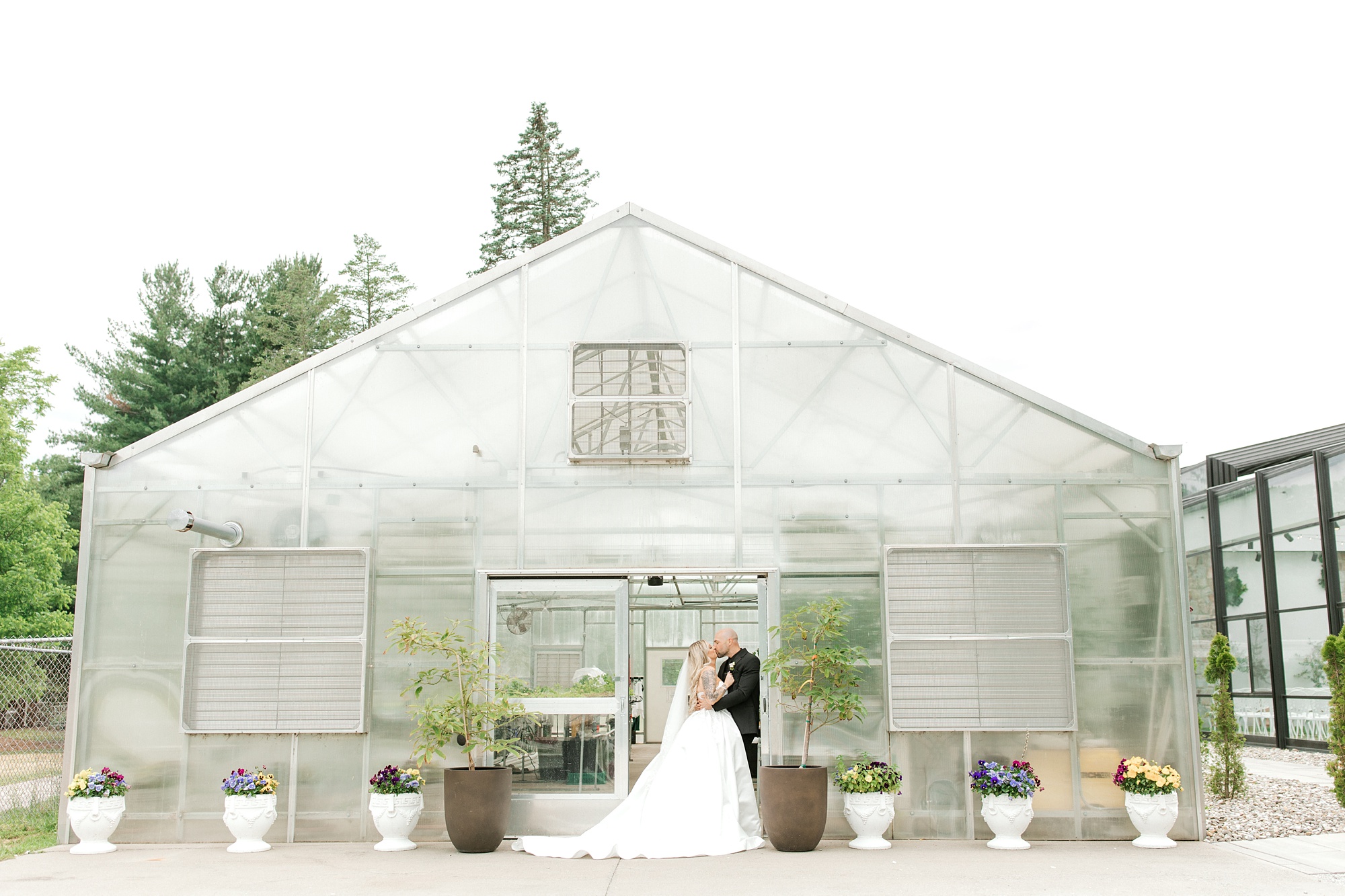 bride and groom kiss outside the greenhouse at the Refinery at Perona Farms