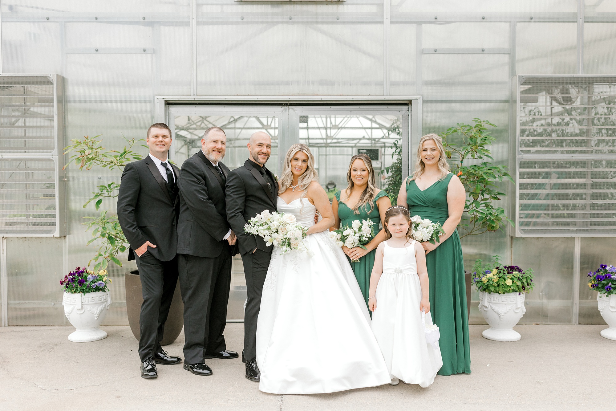 newlyweds smile with wedding party in black and emerald green