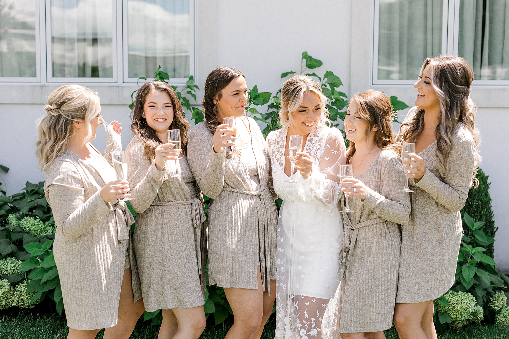 bride and bridesmaids smile together toasting Champagne outside the Mansion at Mountain Lakes