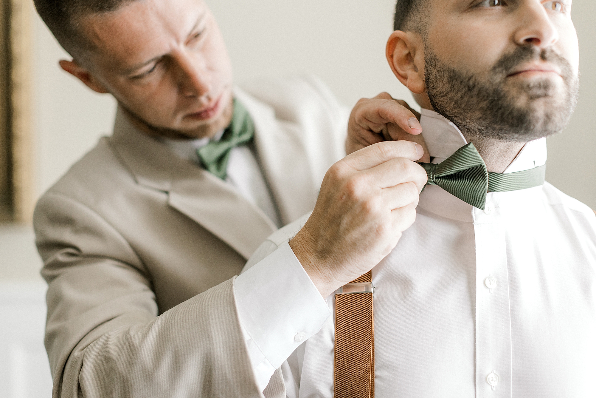 groomsman helps groom with green bow tie at the Mansion at Mountain Lakes