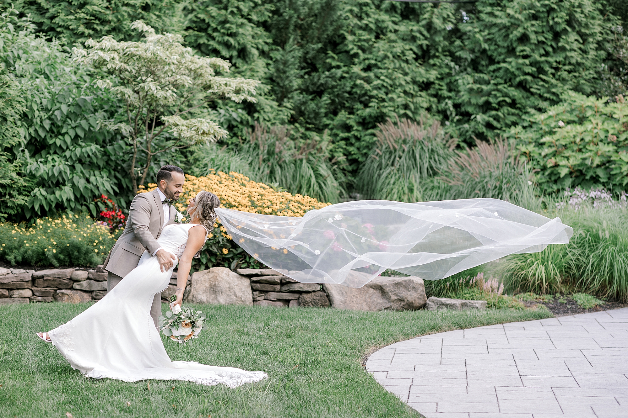 newlyweds kiss while bride's veil floats behind them