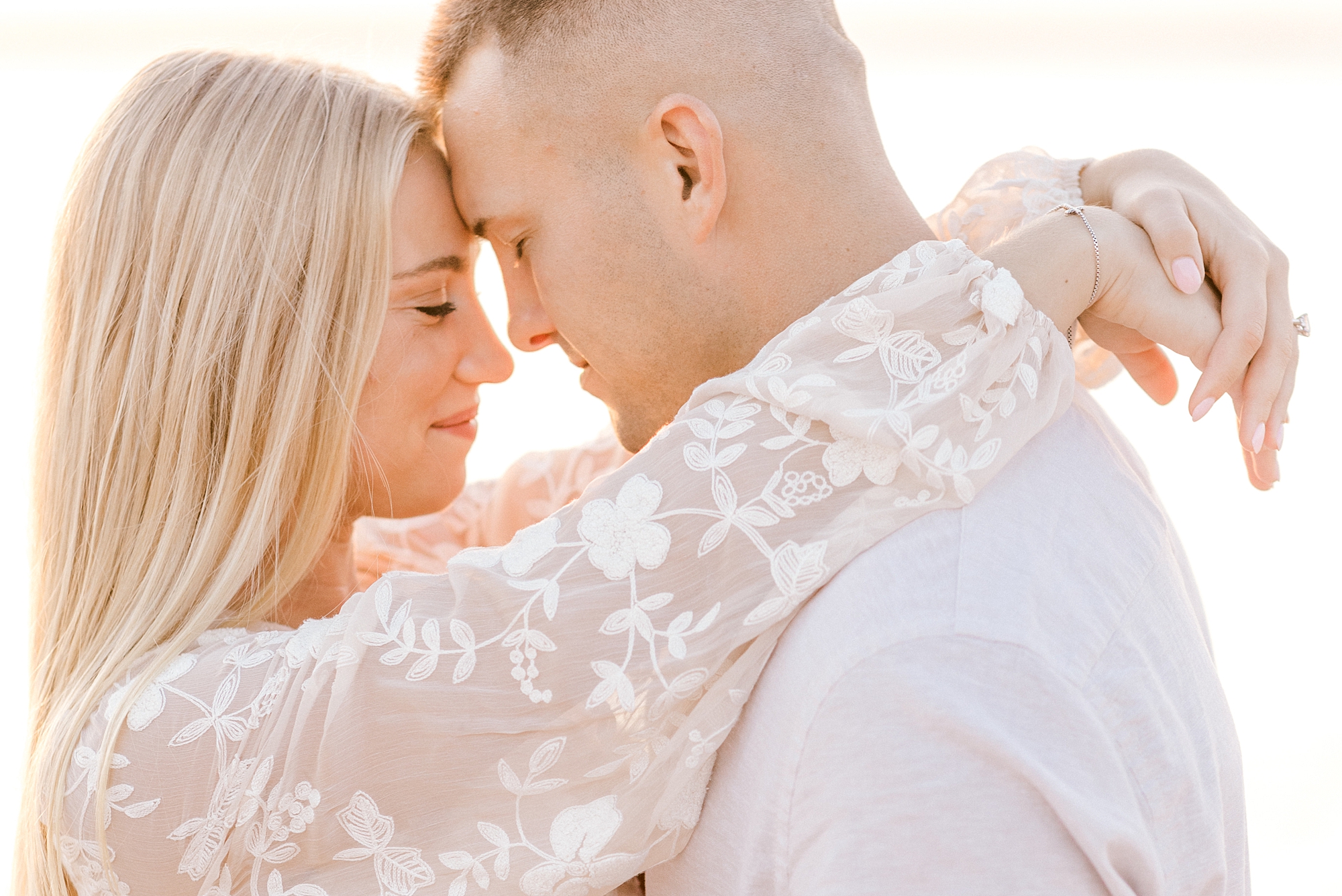 engaged couple hugs leaning heads together during sunset engagement session in Lavallette, NJ