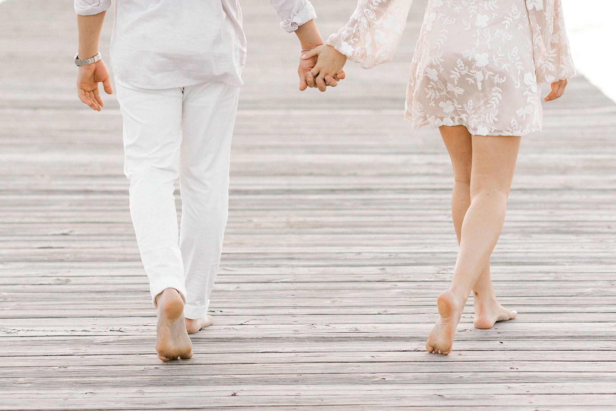 engaged couple holds hands on dock during engagement session in Lavallette, NJ