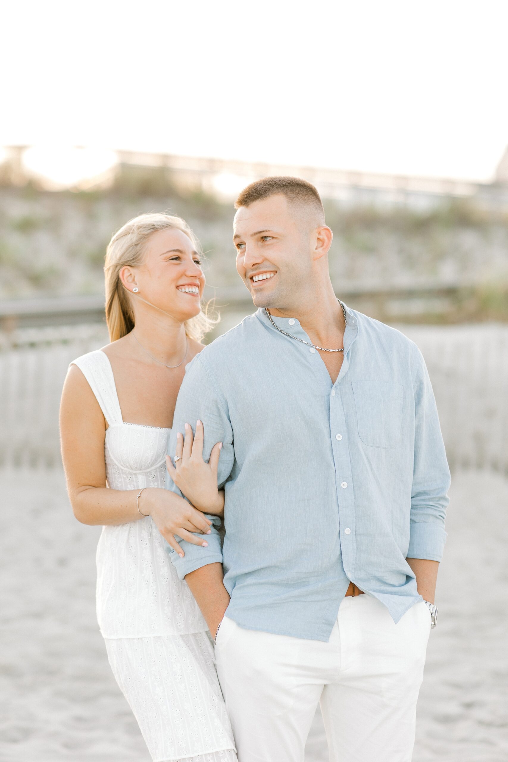 woman holds man from behind smiling up at him during engagement session in Lavallette, NJ