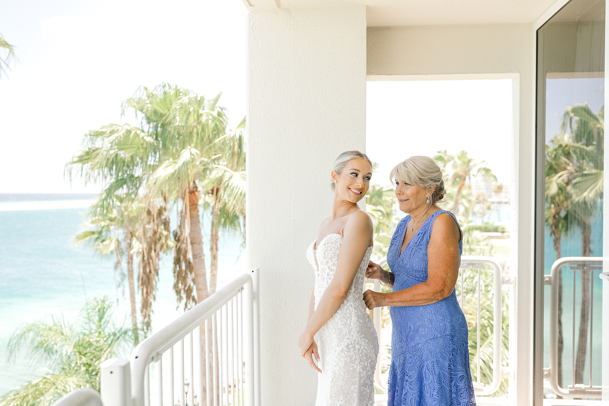 woman in blue dress helps bride into gown on balcony at the Renaissance Aruba