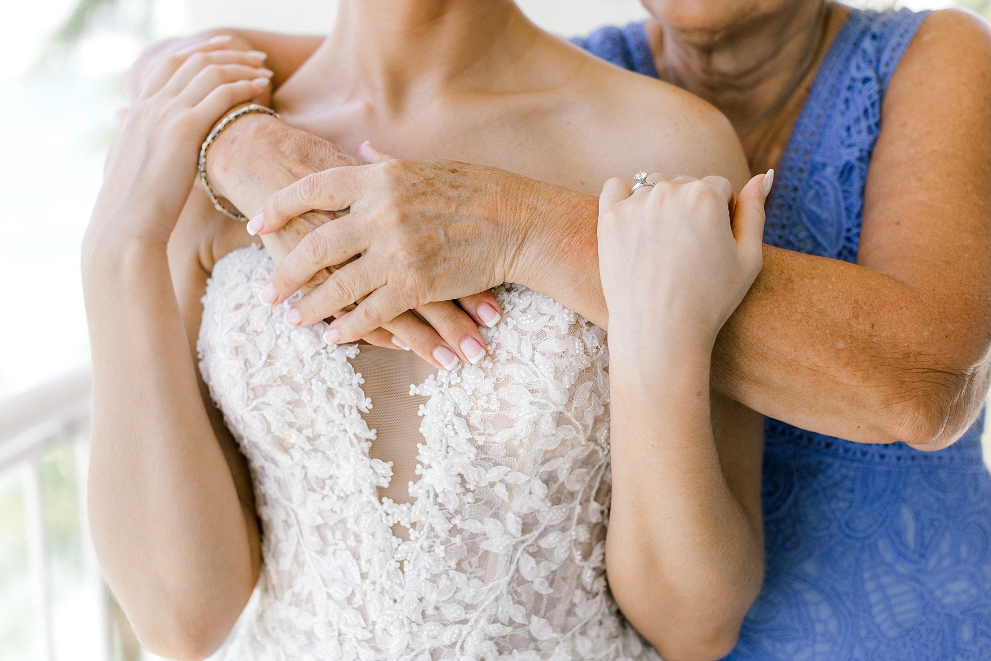 mother hugs bride in lace detailed wedding gown