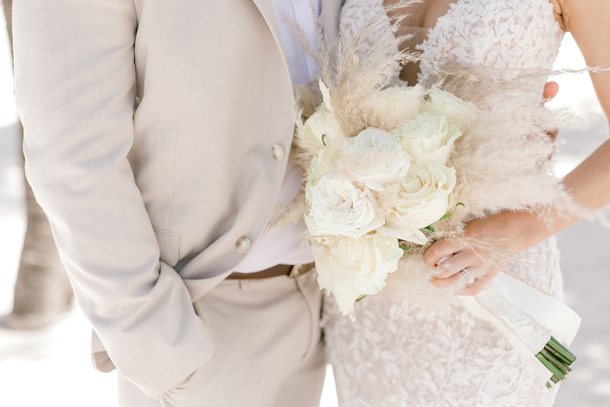 bride hugs groom holding ivory bouquet with tropical flowers