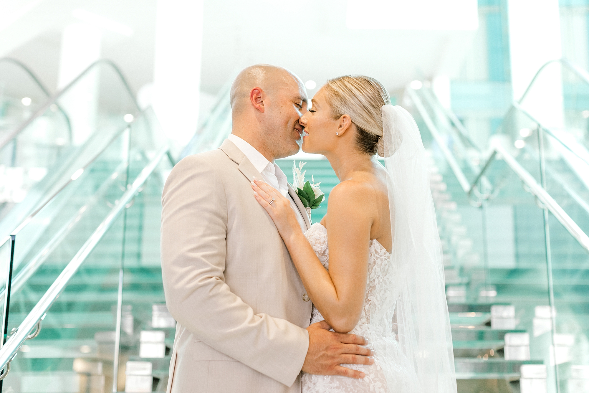 bride and groom kiss on glass steps in lobby at the Renaissance Aruba