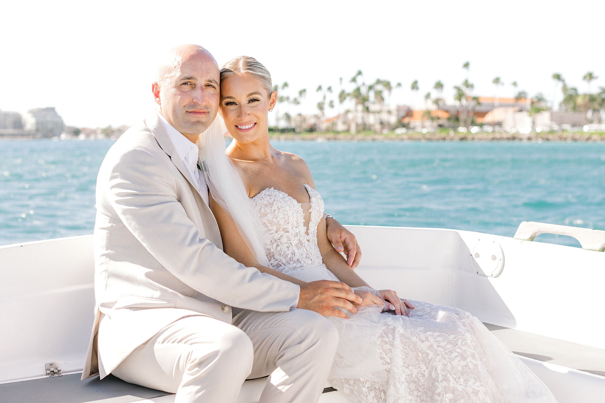 bride snuggles into groom on white seat of boat at Flamingo Island