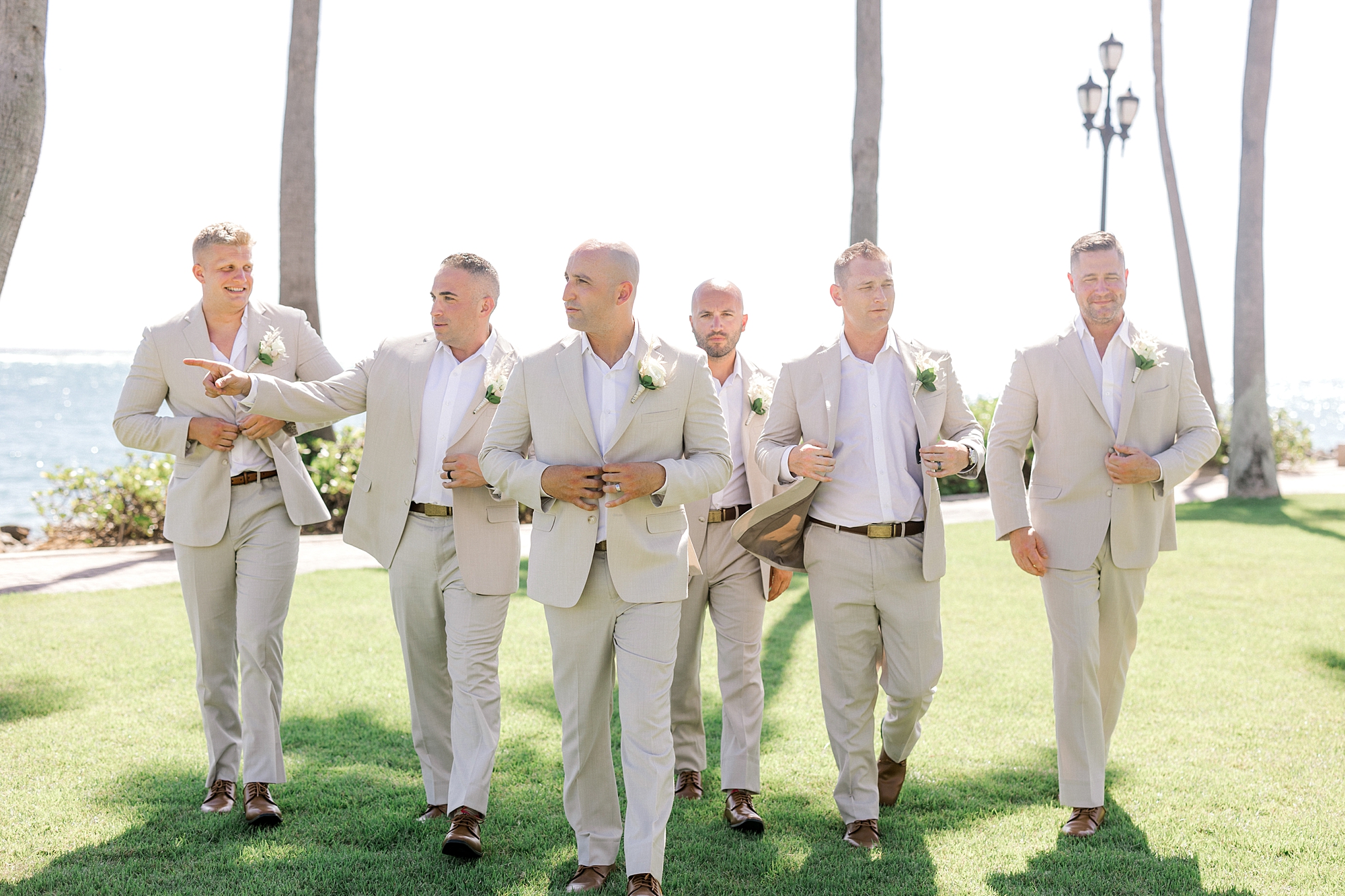 groom walks with groomsmen adjusting tan suit jackets at the Renaissance Aruba
