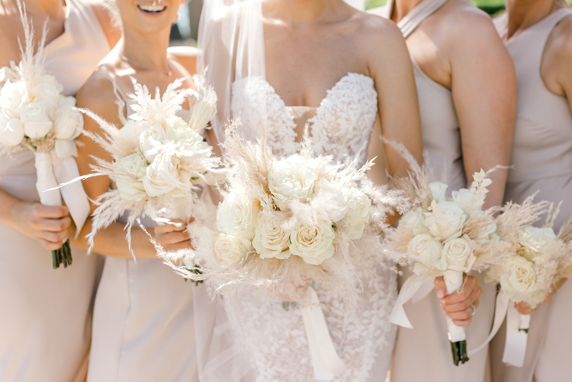 bride and bridesmaids stand together at the Renaissance Aruba holding ivory and tan flowers