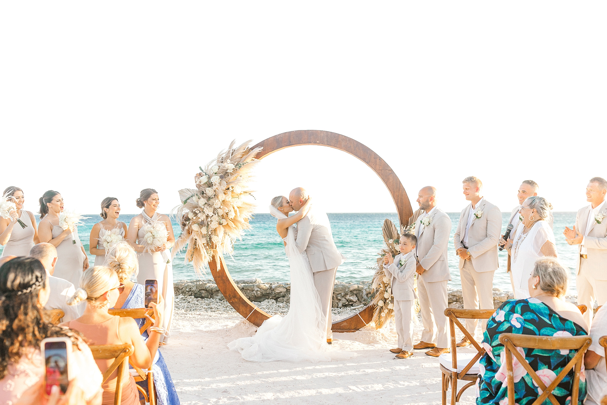 bride and groom kiss during wedding ceremony in front of circular arch on Flamingo Island